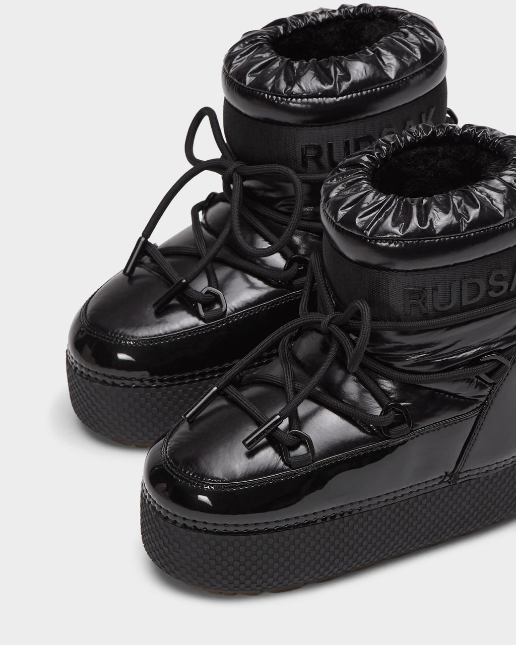 The HARLOW Y - 1223500 Black boots by Rudsak feature shiny, weather-resistant material, thick soles, puffy ankle cuffs, and crisscross laces—perfect stylish and comfy winter boots for kids.