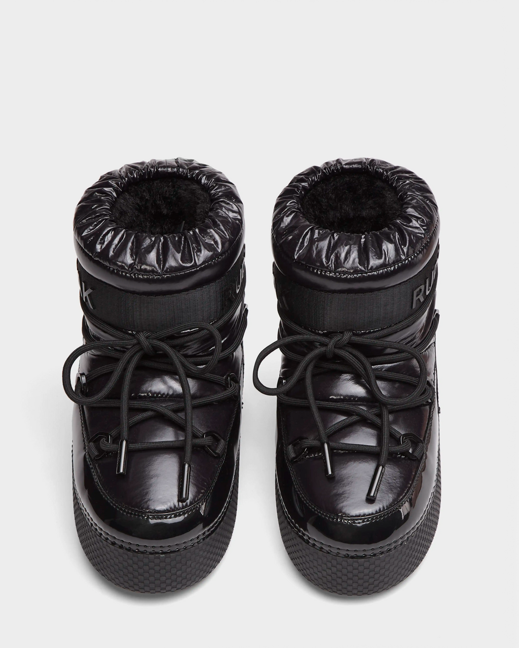 The HARLOW Y - 1223500 Black boots by Rudsak feature shiny black, weather-resistant material, thick soles, round toes, drawstring laces, and padded cuffs; pictured from above on a plain white background.