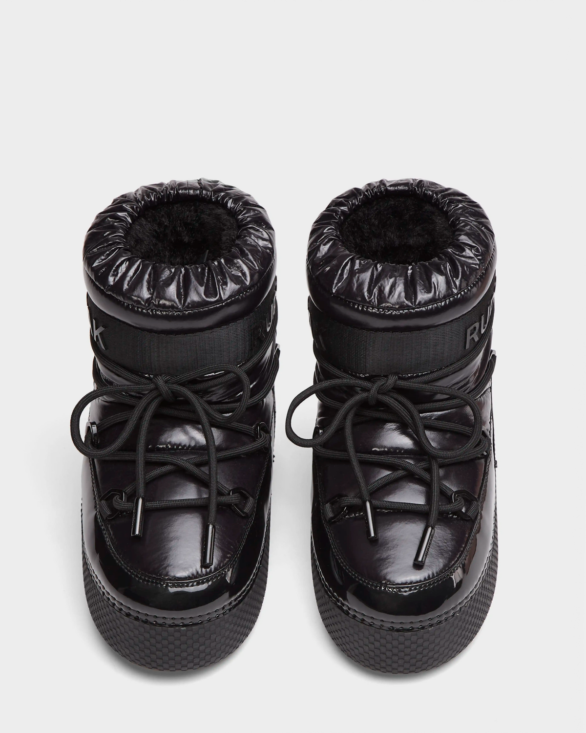 The HARLOW Y - 1223500 Black boots by Rudsak feature shiny black, weather-resistant material, thick soles, round toes, drawstring laces, and padded cuffs; pictured from above on a plain white background.