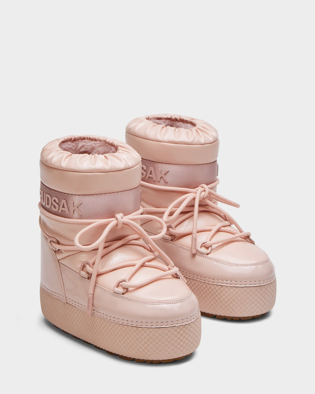 The HARLOW Y - 1223500 Pastel Pink by Rudsak is a pair of light pink kids moon boots with thick soles, round toes, high padded uppers, wrap-around laces, and the Rudsak logo on the cuffs.