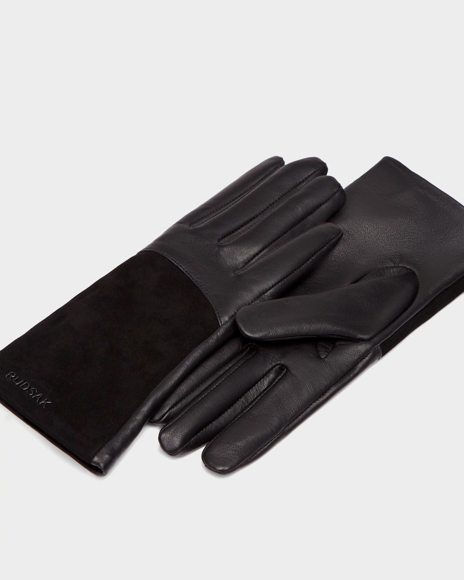 The HELENA - 8424529 Black womens gloves by Rudsak, crafted from black leather and suede with the brand embossed on the suede, are displayed with one atop the other and feature a luxe wool lining for warmth.