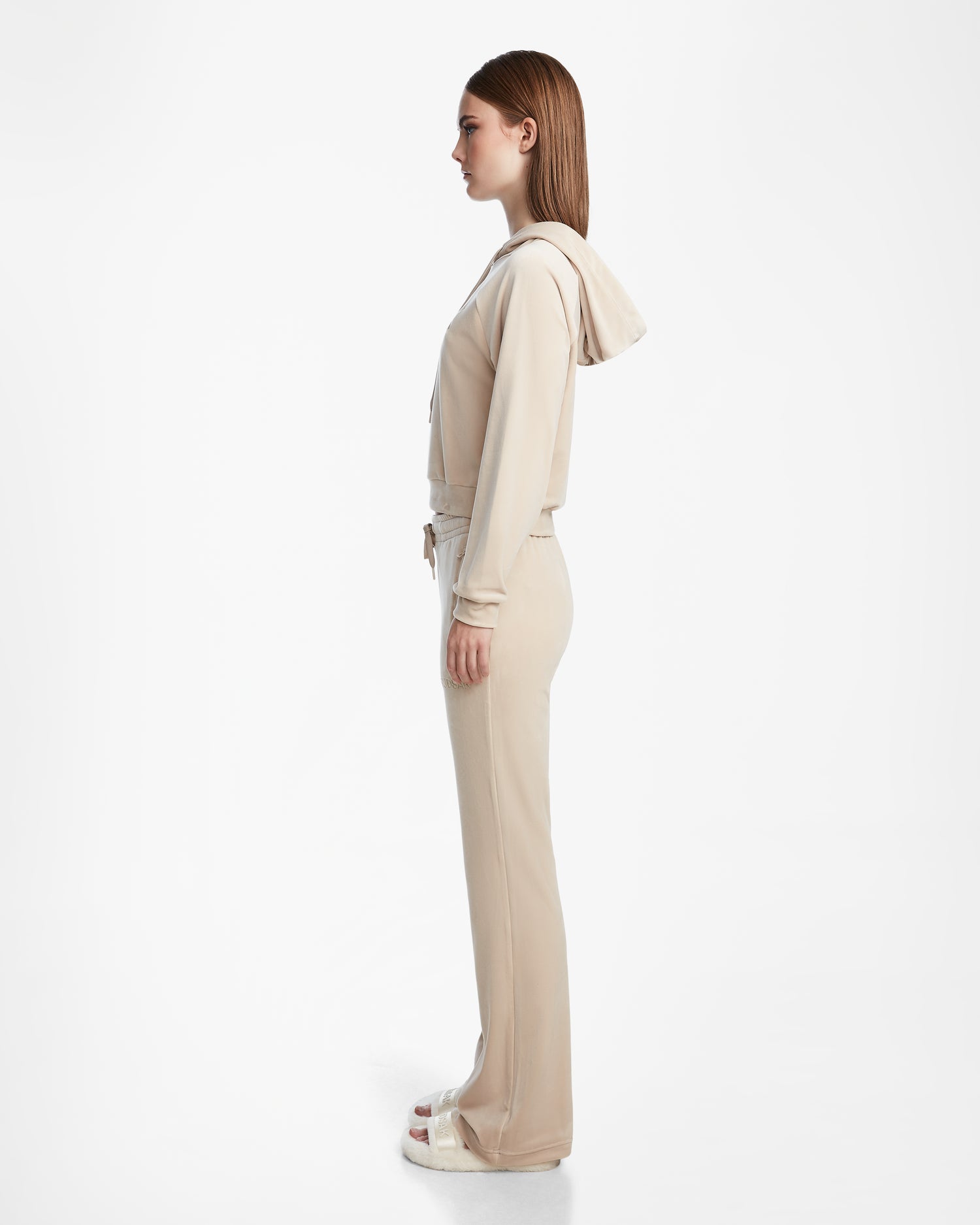A woman stands in profile wearing the Rudsak JODIE - L523501 Cream jacket and straight-leg pants with white platform sandals against a plain white background.