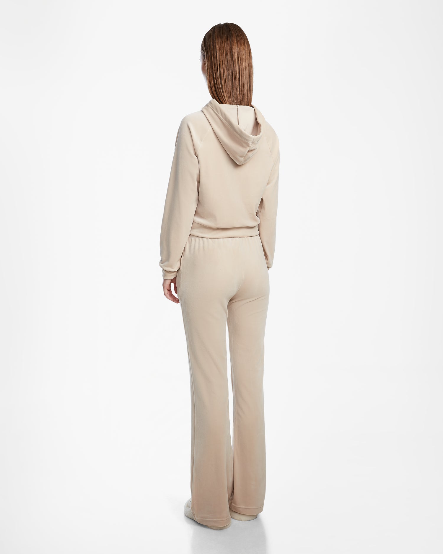 A person with straight, light brown hair stands facing away in a beige hooded Rudsak JODIE - L523501 Cream sweatshirt and women’s straight-leg elastic waist pants against a plain white background.