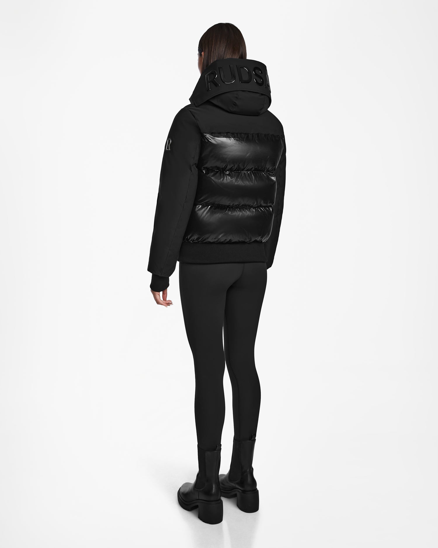 A person wearing the Rudsak JORDY - 9123513 Black W down puffer jacket stands facing away, displaying the back of the coat against a plain white background.