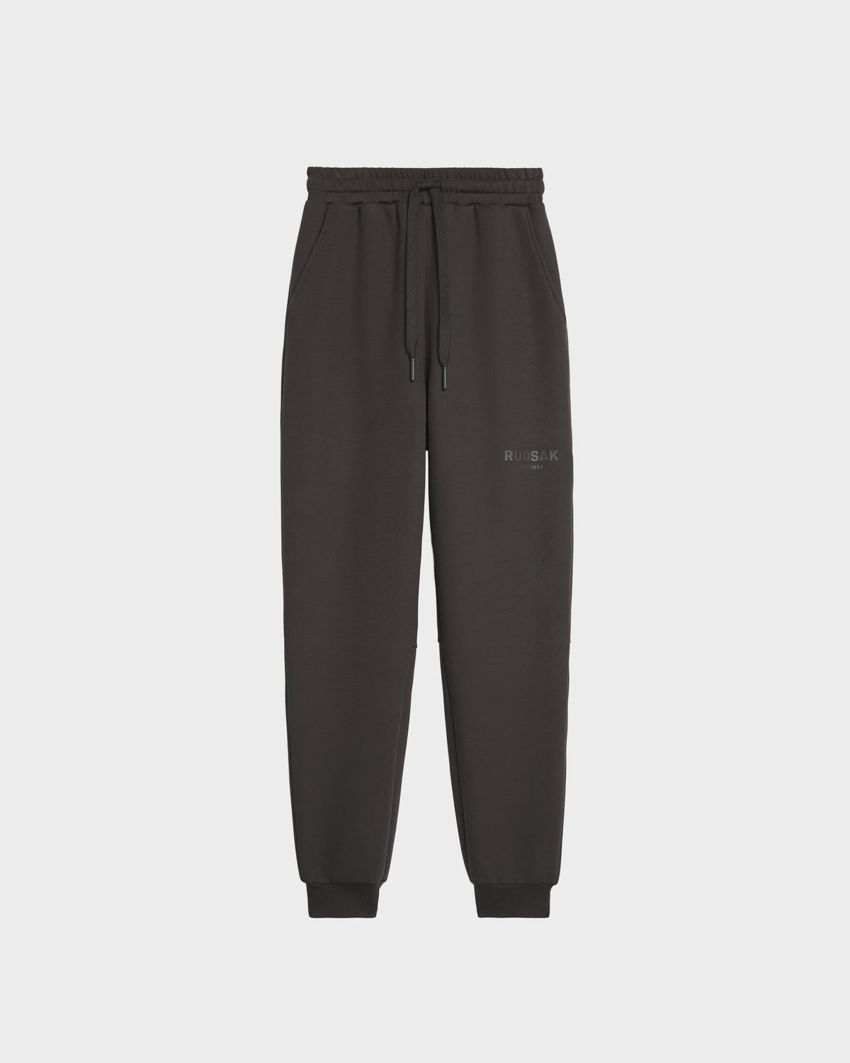 Rudsak JOSS - 9524009 Grey M joggers, made from premium cotton with an elastic waistband, drawstring, side pockets, ribbed cuffs, and a subtle logo on the left thigh, are displayed against a plain light gray background.