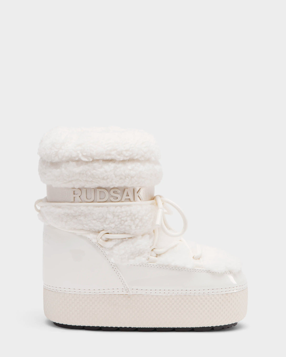 The KATHY Y - 1224500 Iceland by Rudsak is a white, water-repellent winter boot featuring a chunky sole, faux shearling cuff, glossy finish, lace-up detail, and Rudsak branding on the side and strap. Displayed on a plain light background.