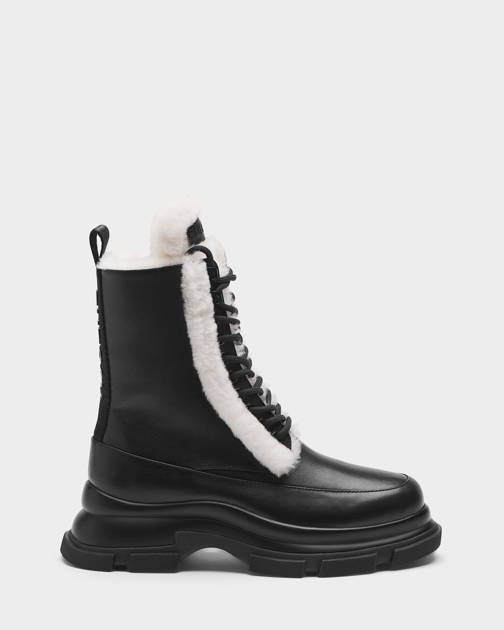 The Rudsak LANA S - 8224537 Black women’s boot features black leather, a chunky sole, and white faux fur lining on the tongue and collar, shown in a side profile against a plain light background.
