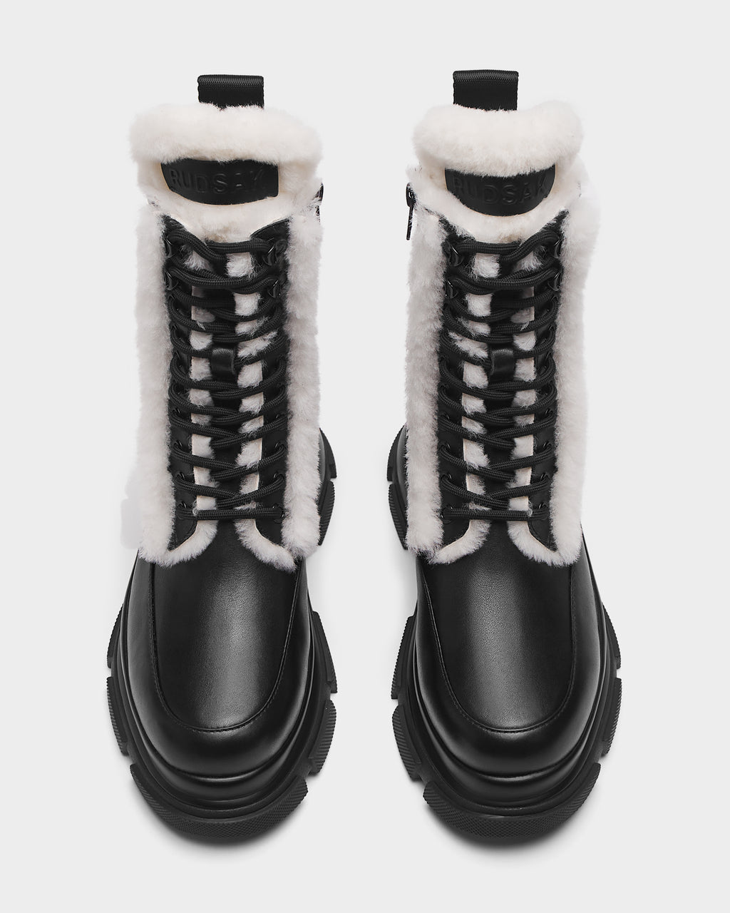 The Rudsak LANA S - 8224537 Black boots feature black leather, chunky soles, and white faux fur trim. Shown from above on a white background, theyre the perfect women’s winter boots for cold days.