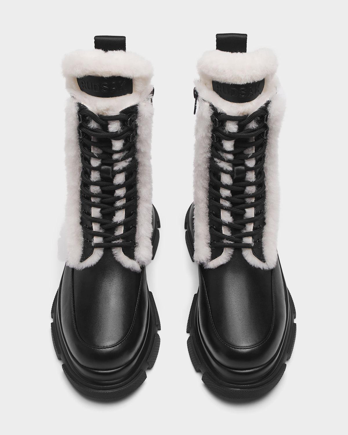 The Rudsak LANA S - 8224537 Black boots feature black leather, chunky soles, and white faux fur trim. Shown from above on a white background, theyre the perfect women’s winter boots for cold days.