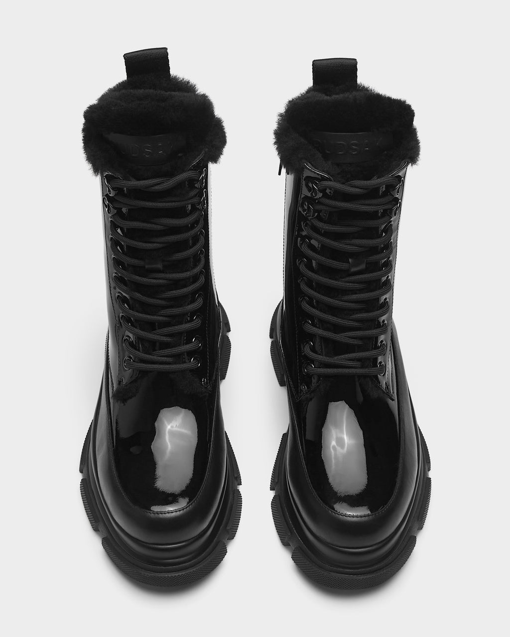 The LANA - 8223506 BLACK boots by Rudsak are shiny black mid-calf lace-up boots with thick soles and faux fur trim around the ankle, shown from above on a white background.