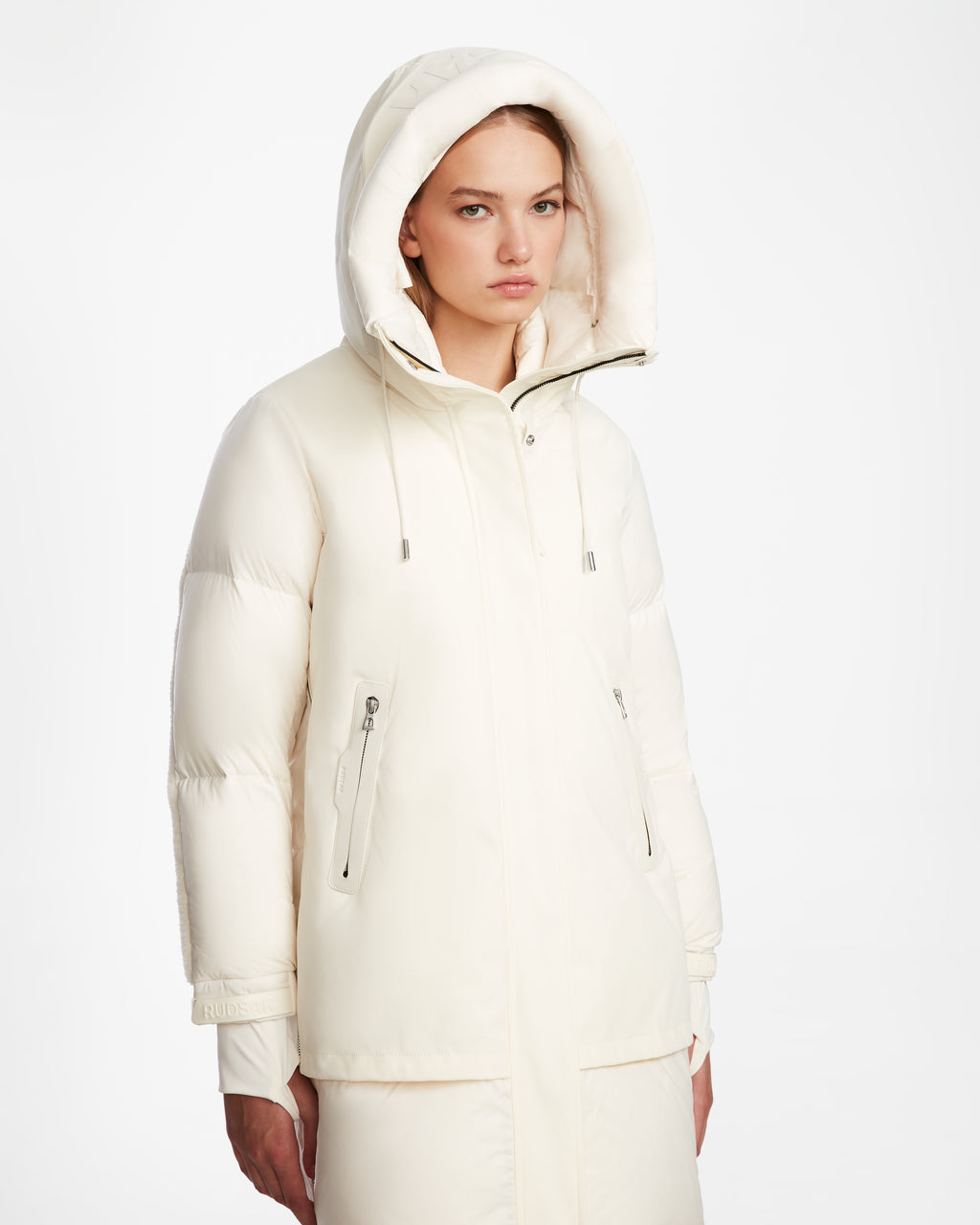 A woman models the Rudsak LAYAN - 8124576 Iceland cream-colored womens down parka with a high collar, standing slightly sideways against a plain white background with a neutral expression.