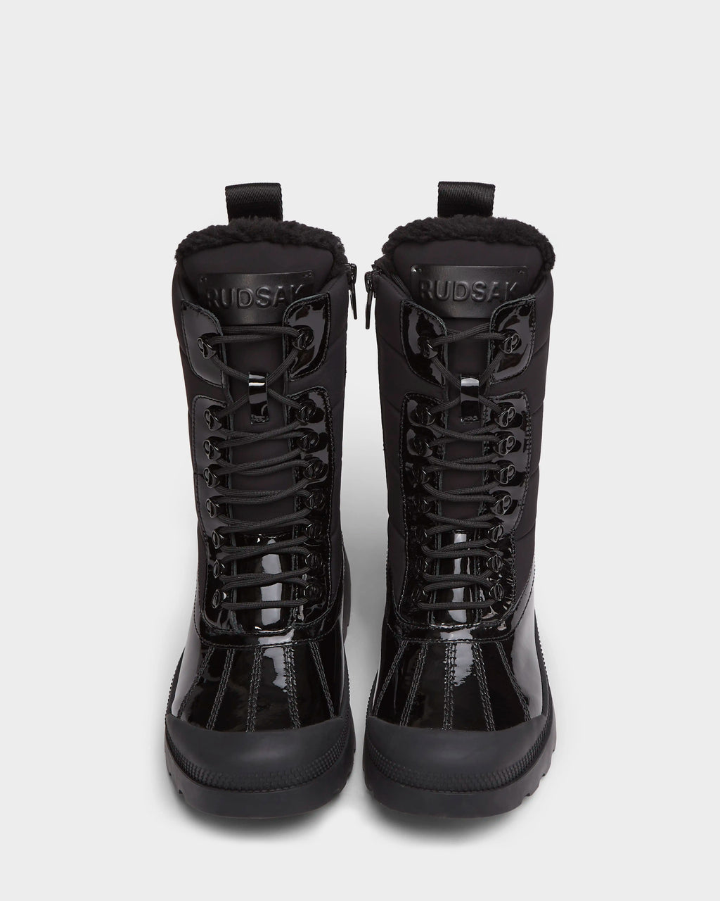 A pair of LEX - 8224534 Black women’s winter boots by Rudsak with rugged soles and shearling-lined collars, shown upright on a white background. The water-resistant boots display the Rudsak brand name on each tongue.