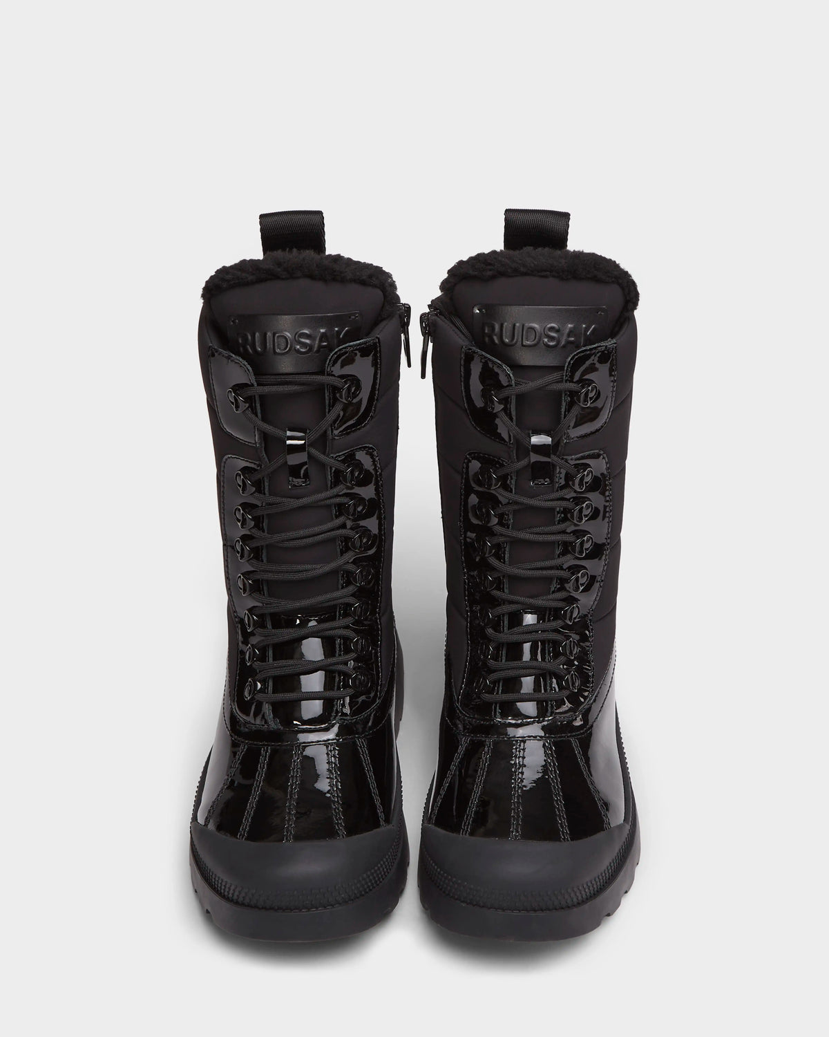 A pair of LEX - 8224534 Black women’s winter boots by Rudsak with rugged soles and shearling-lined collars, shown upright on a white background. The water-resistant boots display the Rudsak brand name on each tongue.