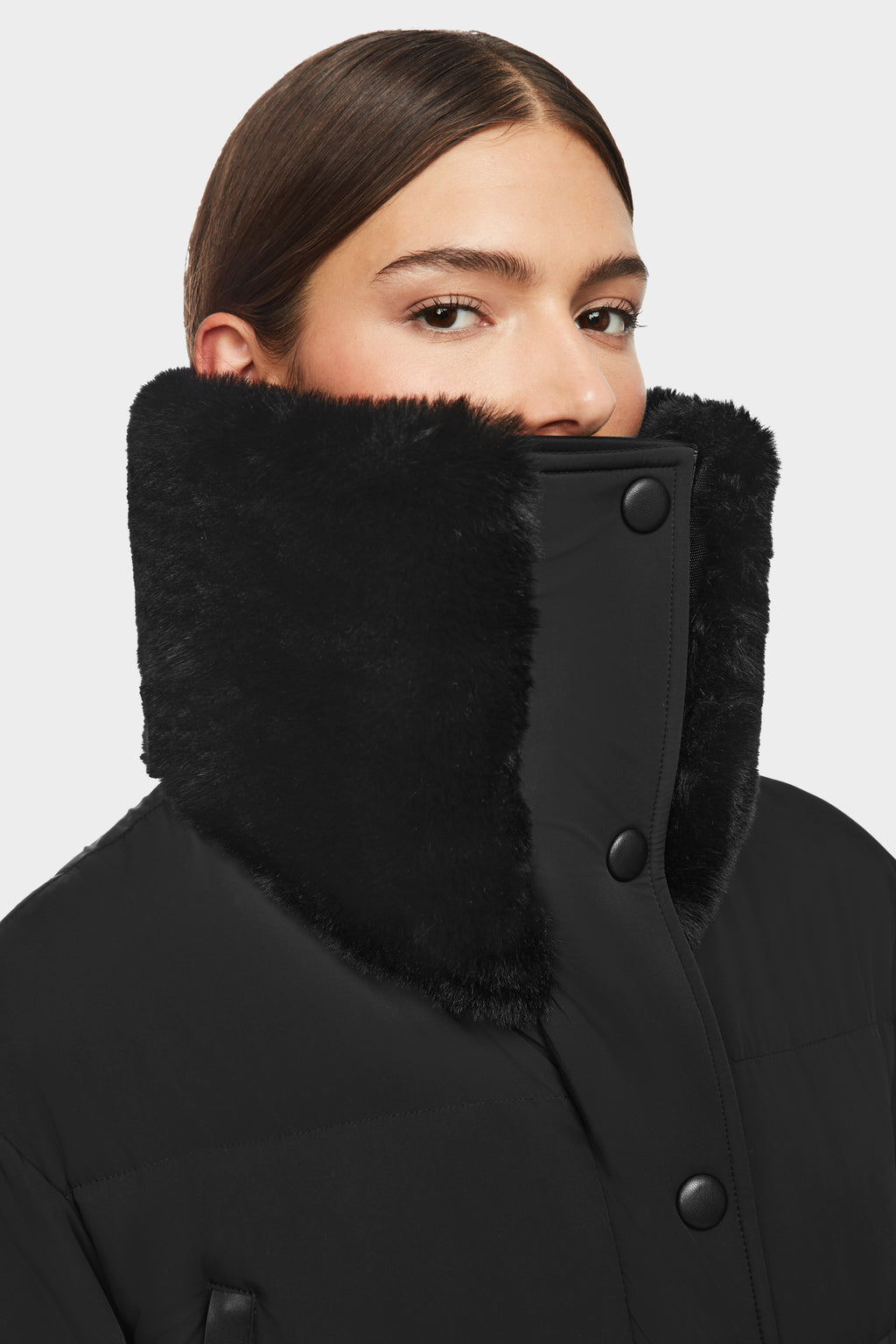 A woman with straight brown hair wears the Rudsak LOVE - 8124724 Black coat, featuring a high plush faux fur collar, large black buttons, and a matte finish against a plain white background.