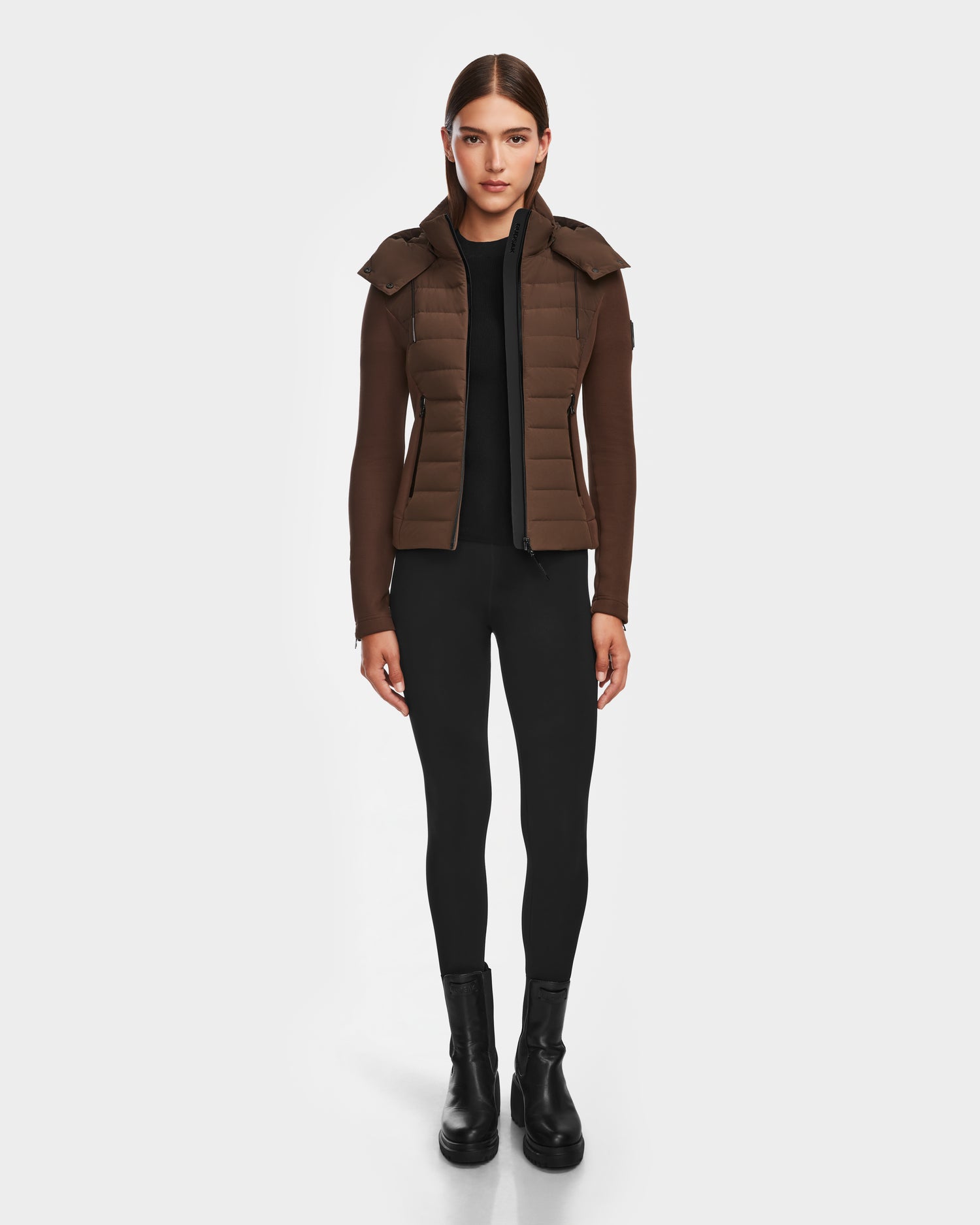 A person stands facing forward wearing the Rudsak MABS - 8124825 Espresso womens lightweight short jacket with shoulder flaps over a black shirt, leggings, and ankle boots against a plain white background.