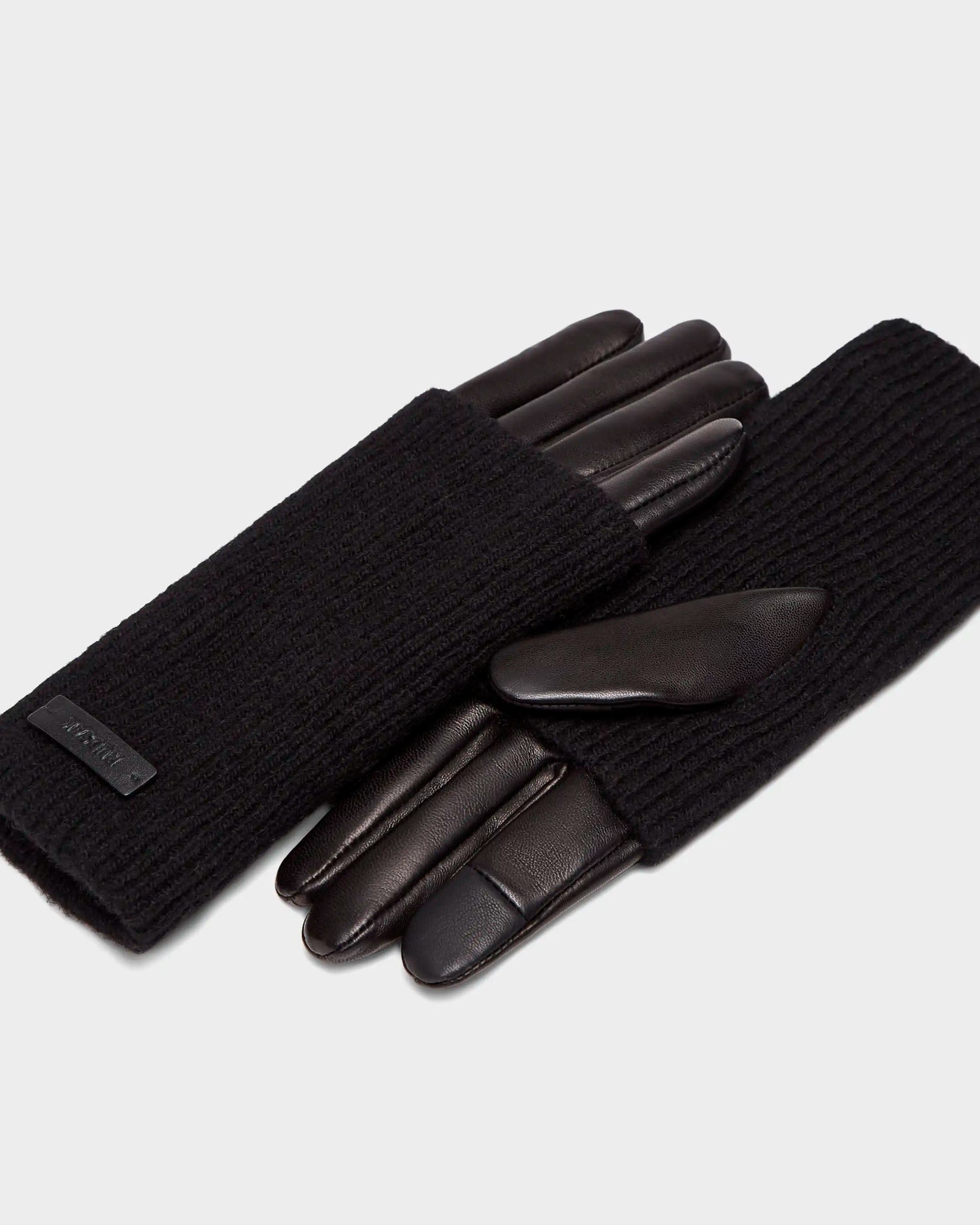The MARINE - 8424516 Black women’s gloves by Rudsak pair chic black leather palms with ribbed knit wool backs, shown against a plain light gray background.