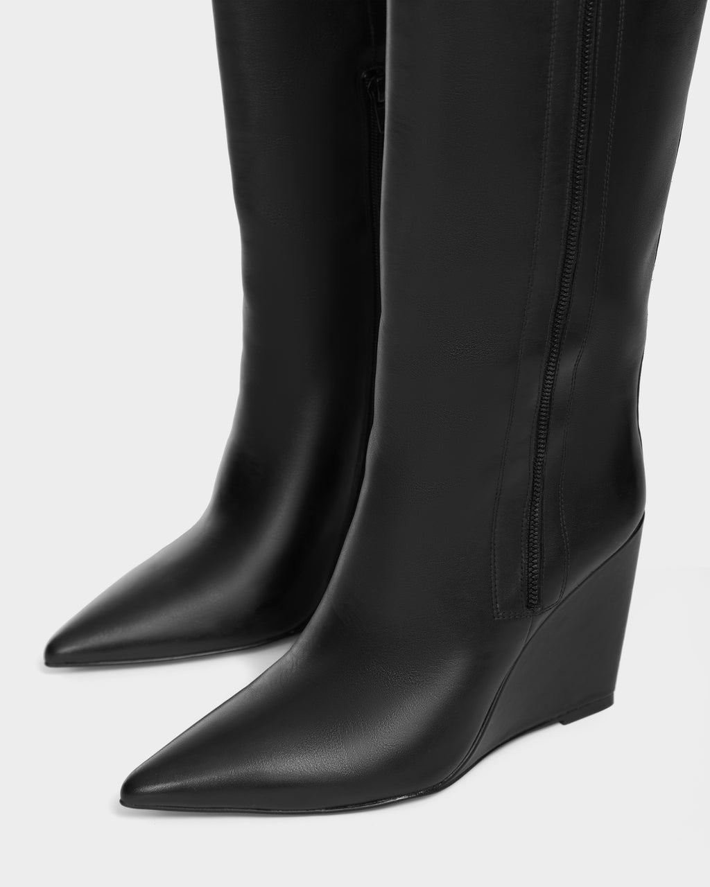 Close-up of NANCY - 8224507 Black womens wedge leather boots by Rudsak, featuring pointed toes, side zippers, and a high shaft design, set against a plain white background.
