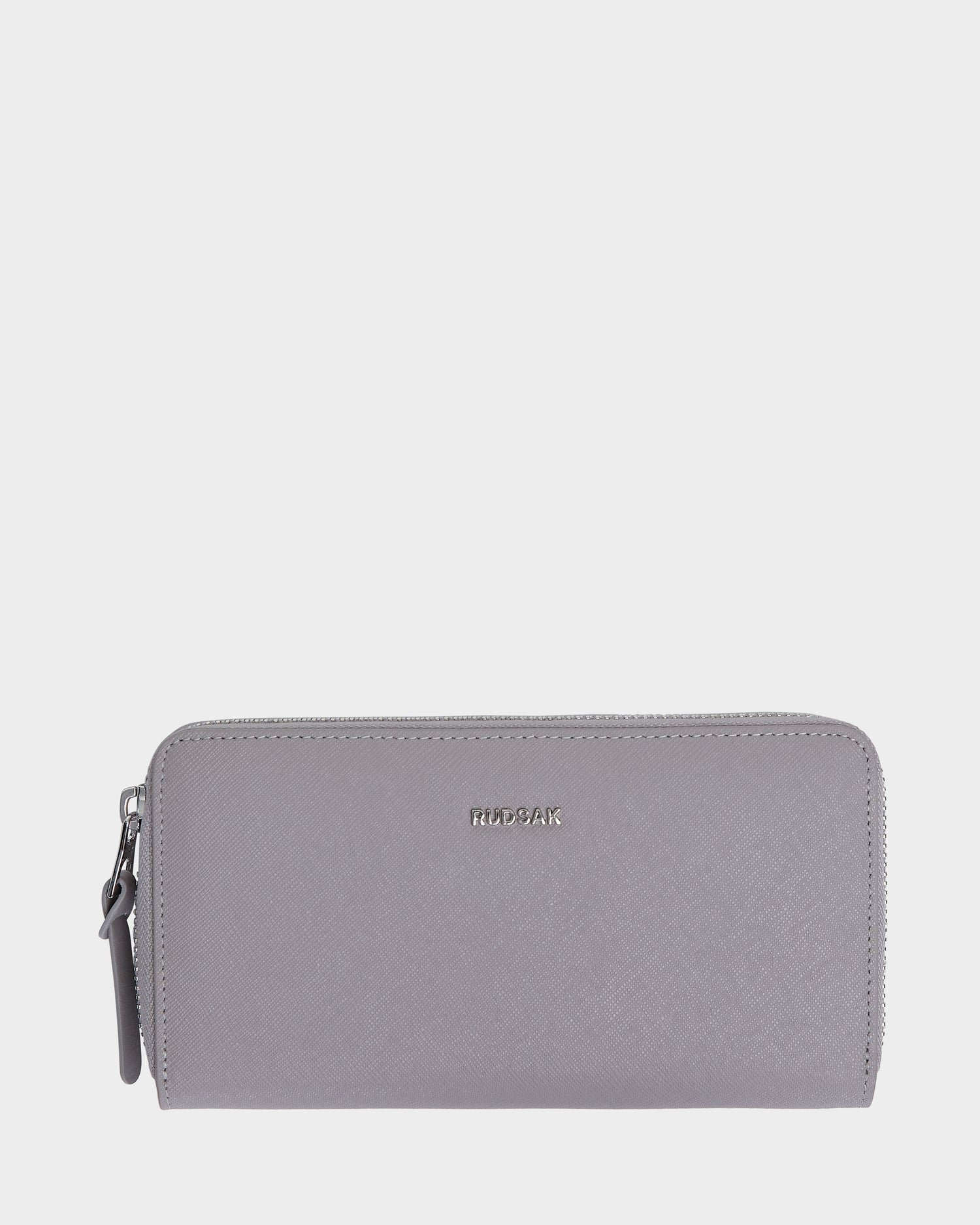 The Rudsak NYLA - L424502 Grey is a womens light gray leather wallet with a textured surface, zippered compartment, and small metallic logo on the front, shown against a white background.