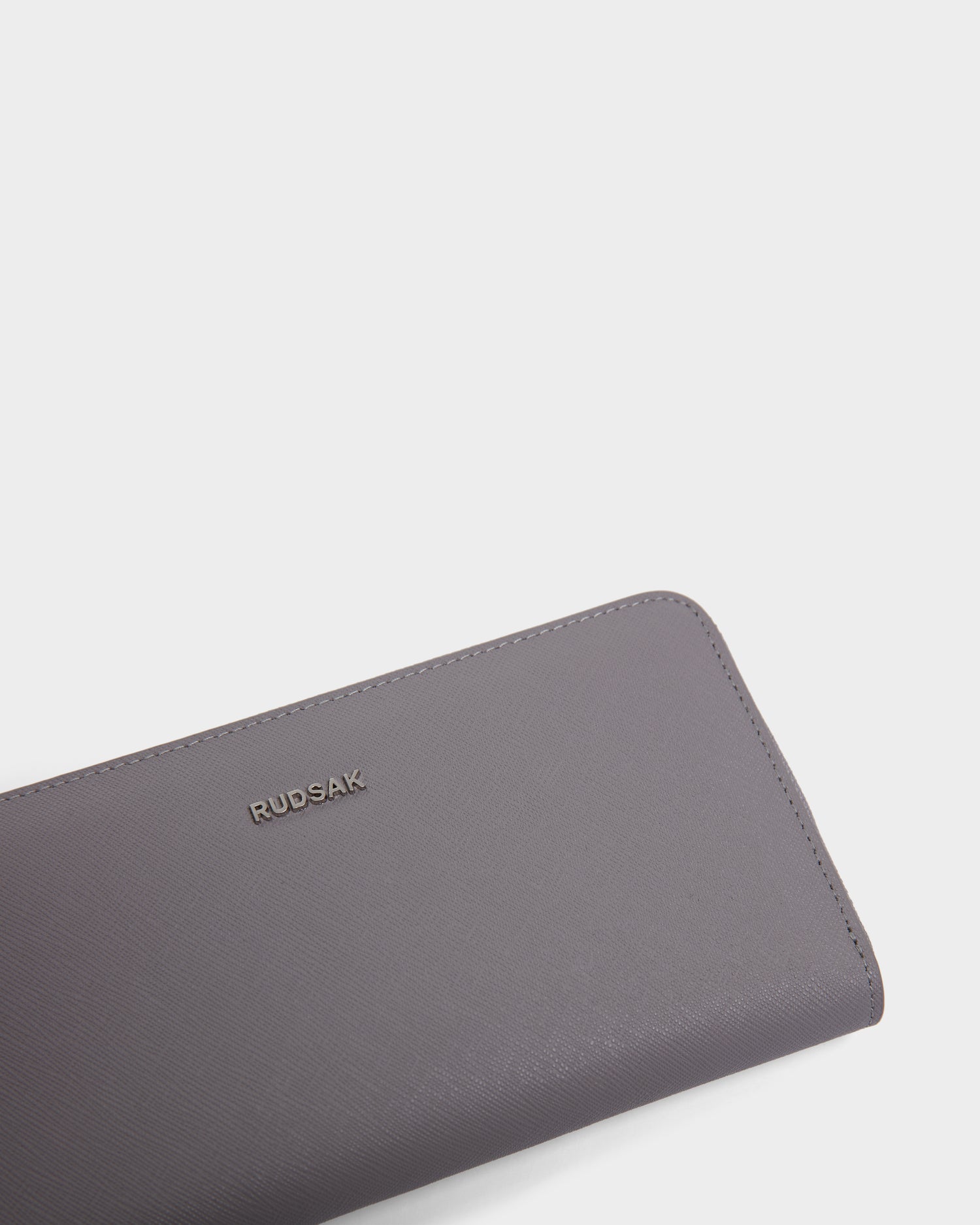 A close-up of the Rudsak NYLA - L424502 Grey womens leather wallet featuring a textured surface, cardholder slots, and metallic brand lettering, displayed against a plain white background.