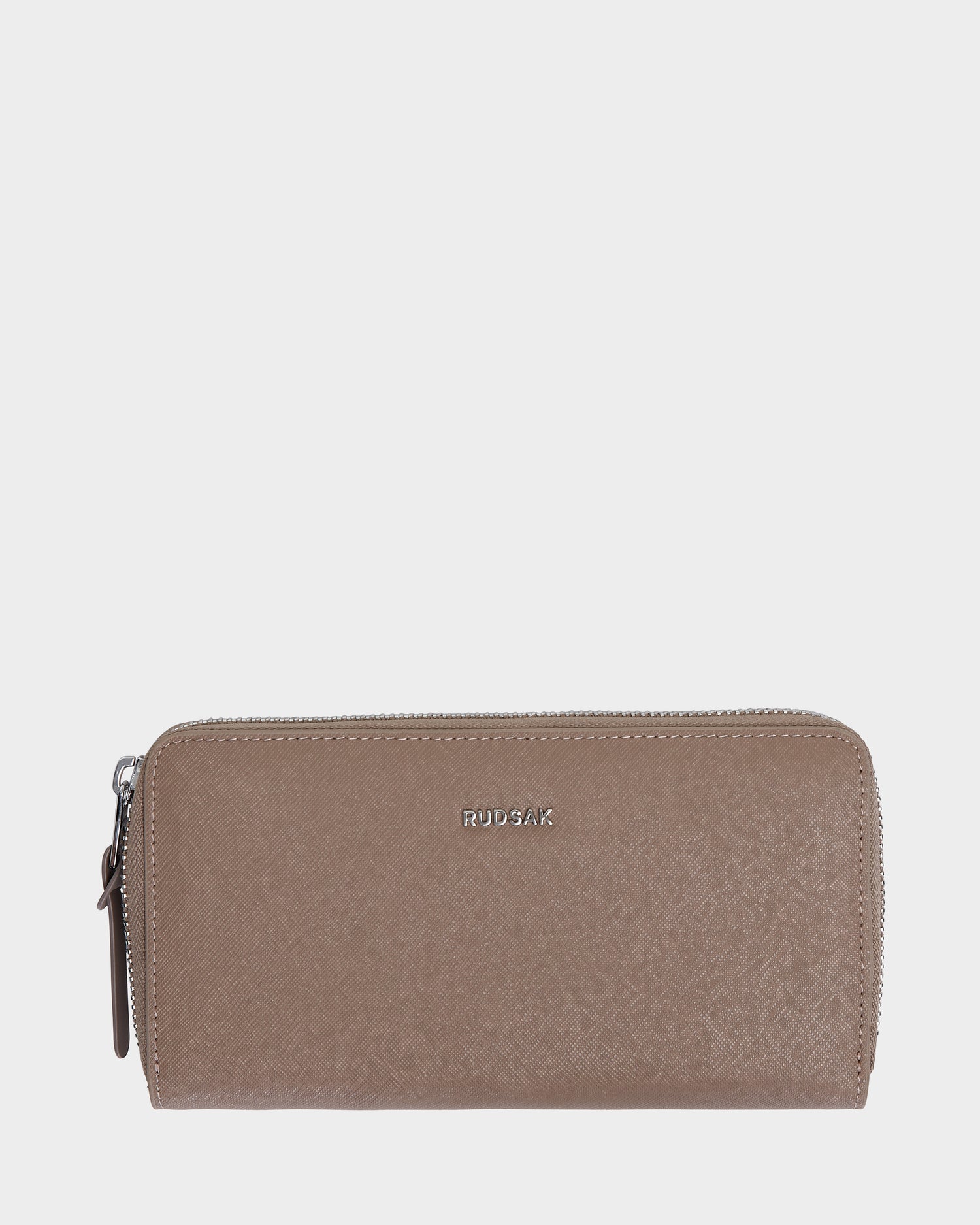 The Rudsak NYLA - L424502 Sand is a taupe women’s leather wallet with a textured finish, cardholder slots, silver zipper, and “RUDSAK” embossed in silver on the front, shown on a plain white background.