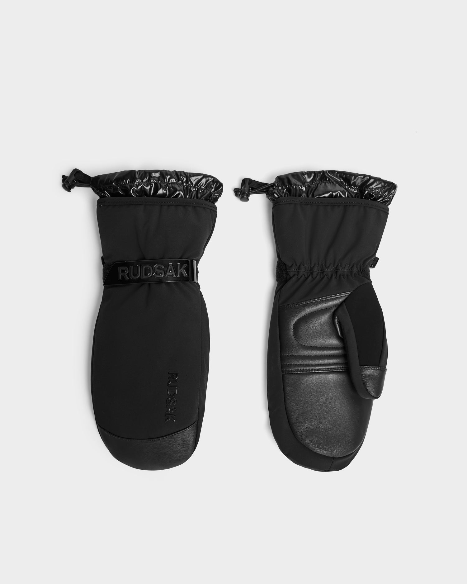 A pair of Rudsak OLTEN - 8424513 black insulated winter mittens with adjustable wrist straps and drawstring cuffs, displayed from palm and back views on a plain light background.