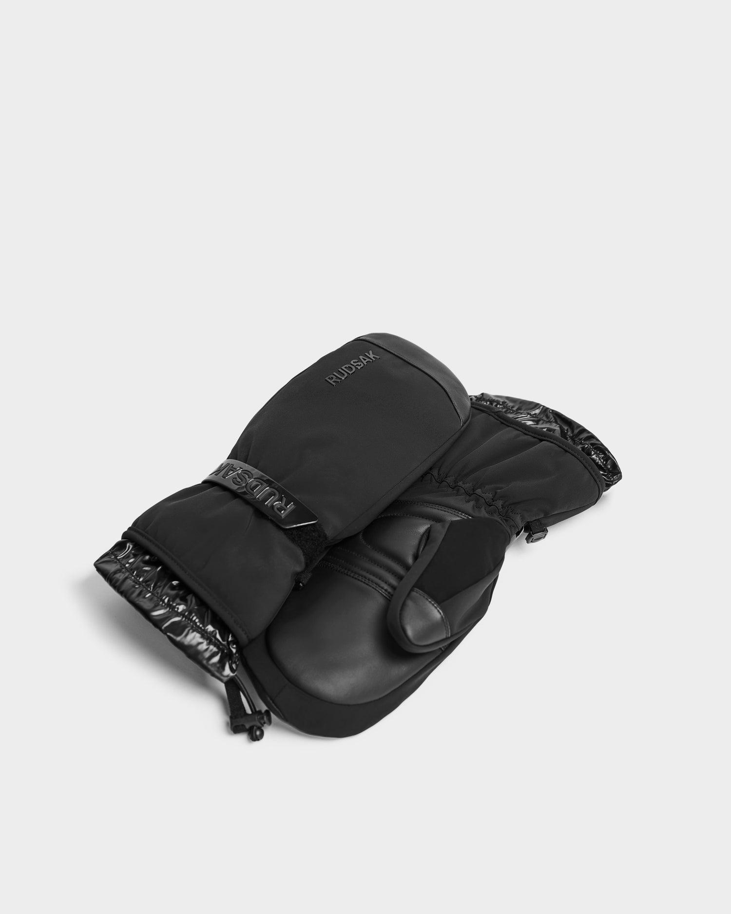 A pair of OLTEN - 8424513 Black insulated winter mittens by Rudsak with adjustable wrist straps and subtle branding, displayed on a light grey background.