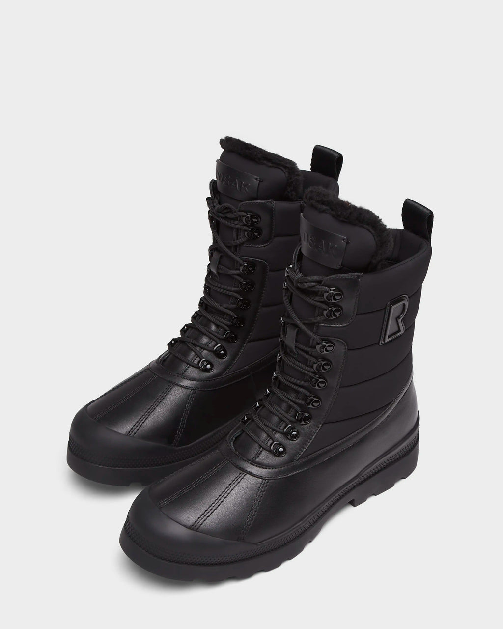 The Rudsak REAGAN - 6224501 Black boots feature a lace-up design, thick rubber soles, and faux fur lining—ideal men’s winter boots for warmth and style, shown against a plain white background.