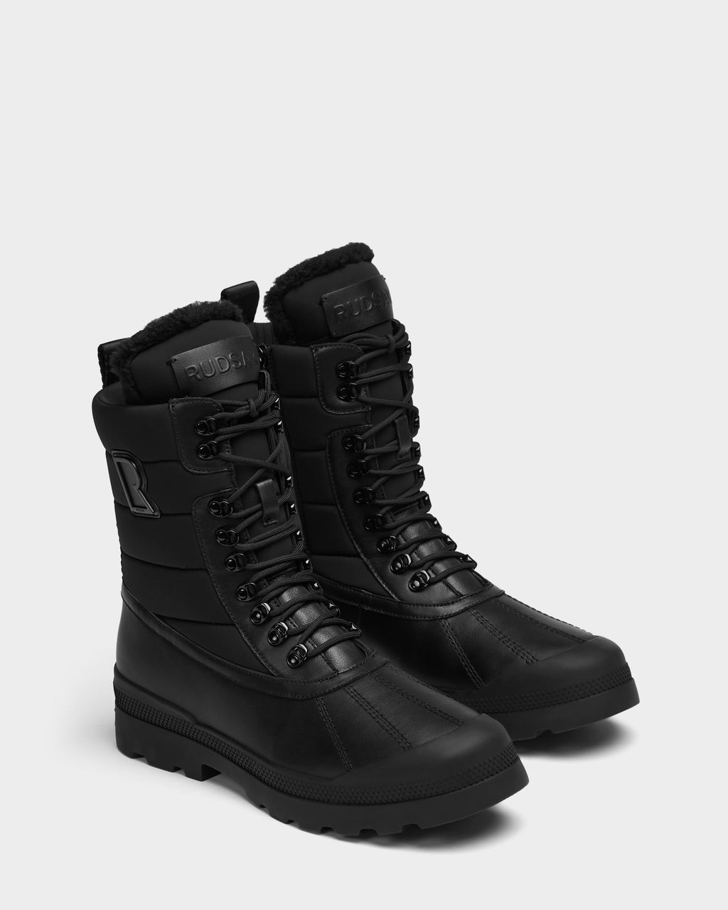 A pair of REAGAN - 6225046 Black men’s winter boots featuring black lace-up fronts, quilted shafts, rubberized toe caps, and faux-fur lining at the collars.