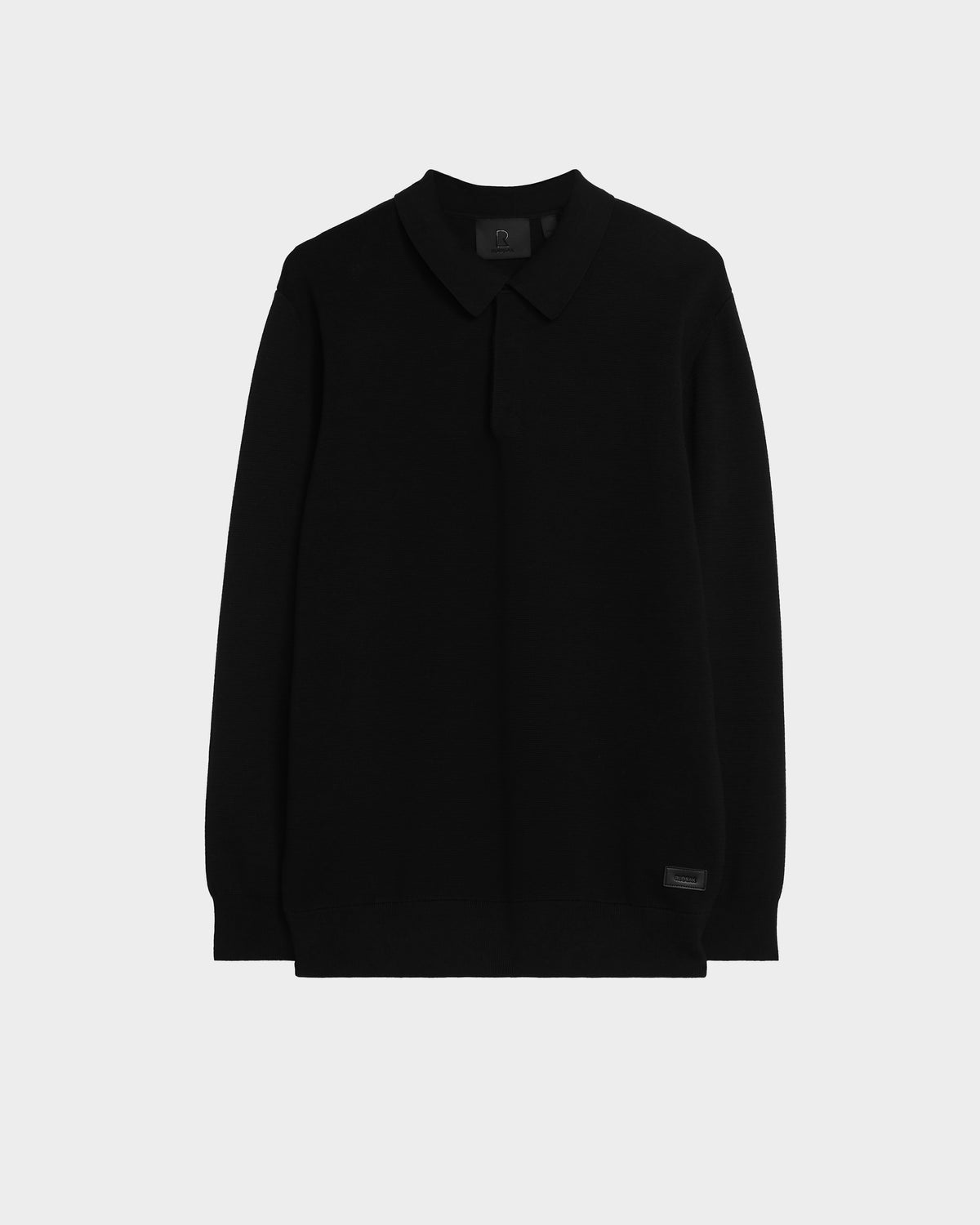 The Rudsak RICHARD - 6524529 Black is a mens long sleeve polo with a collar, shown on a light gray background. Its plain, minimalist design makes it a versatile wardrobe staple.