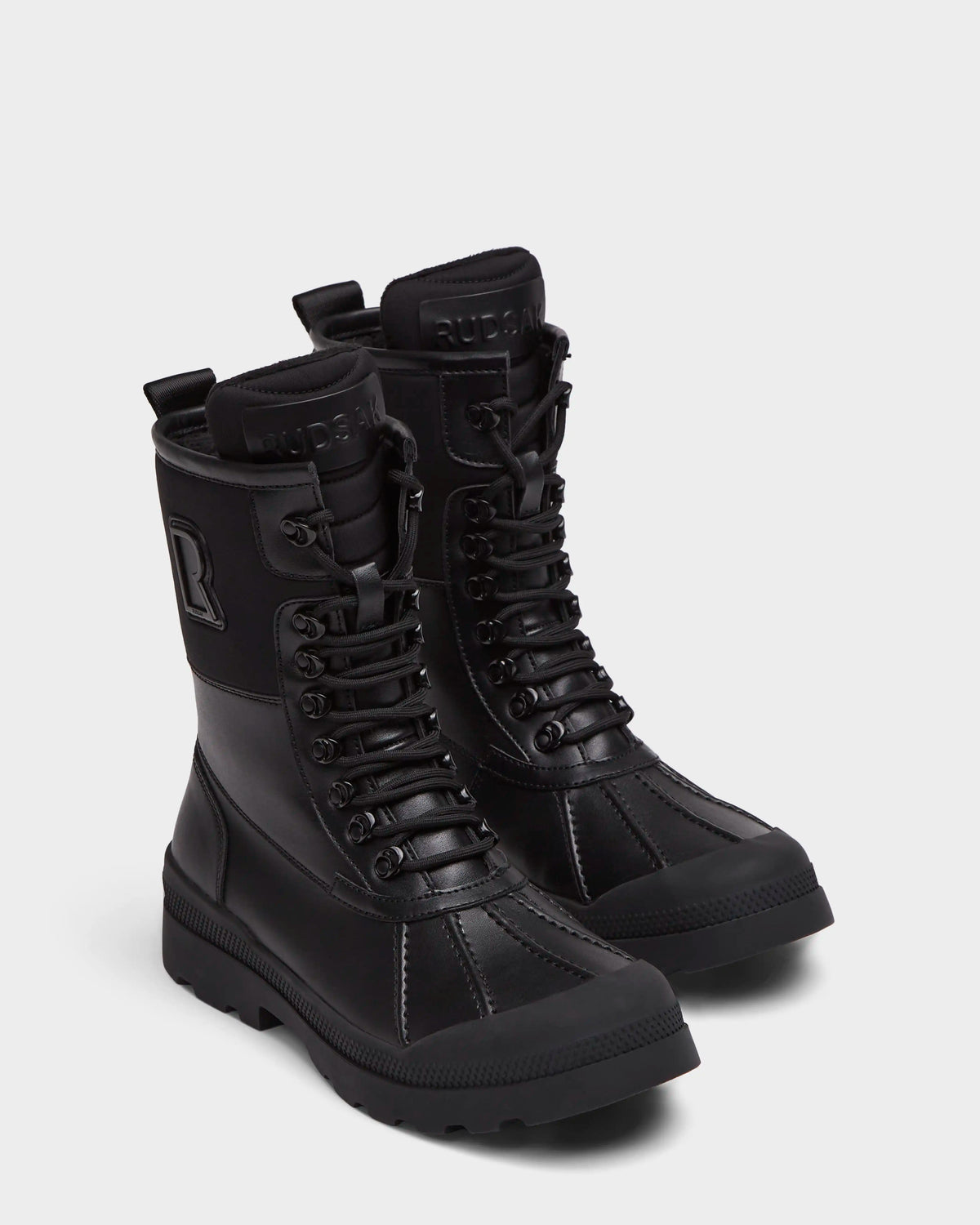 The Rudsak RITA - L222502 Black women's winter boots feature mid-calf lace-up design, weather-treated leather, rugged soles, and embossed branding on the tongue and side, shown on a plain light background.