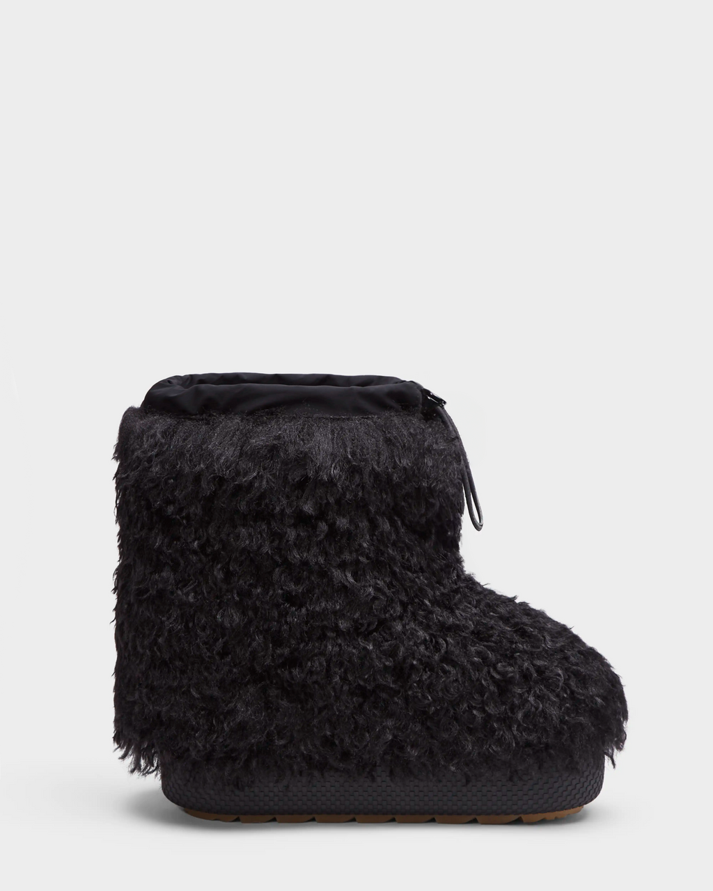 The Rudsak ROSSY - 8224518 Black is a single black slip-on winter boot with a thick, curly faux fur exterior, rounded toe, and flat rubber sole, inspired by Mongolian fur boots and displayed against a plain white background.