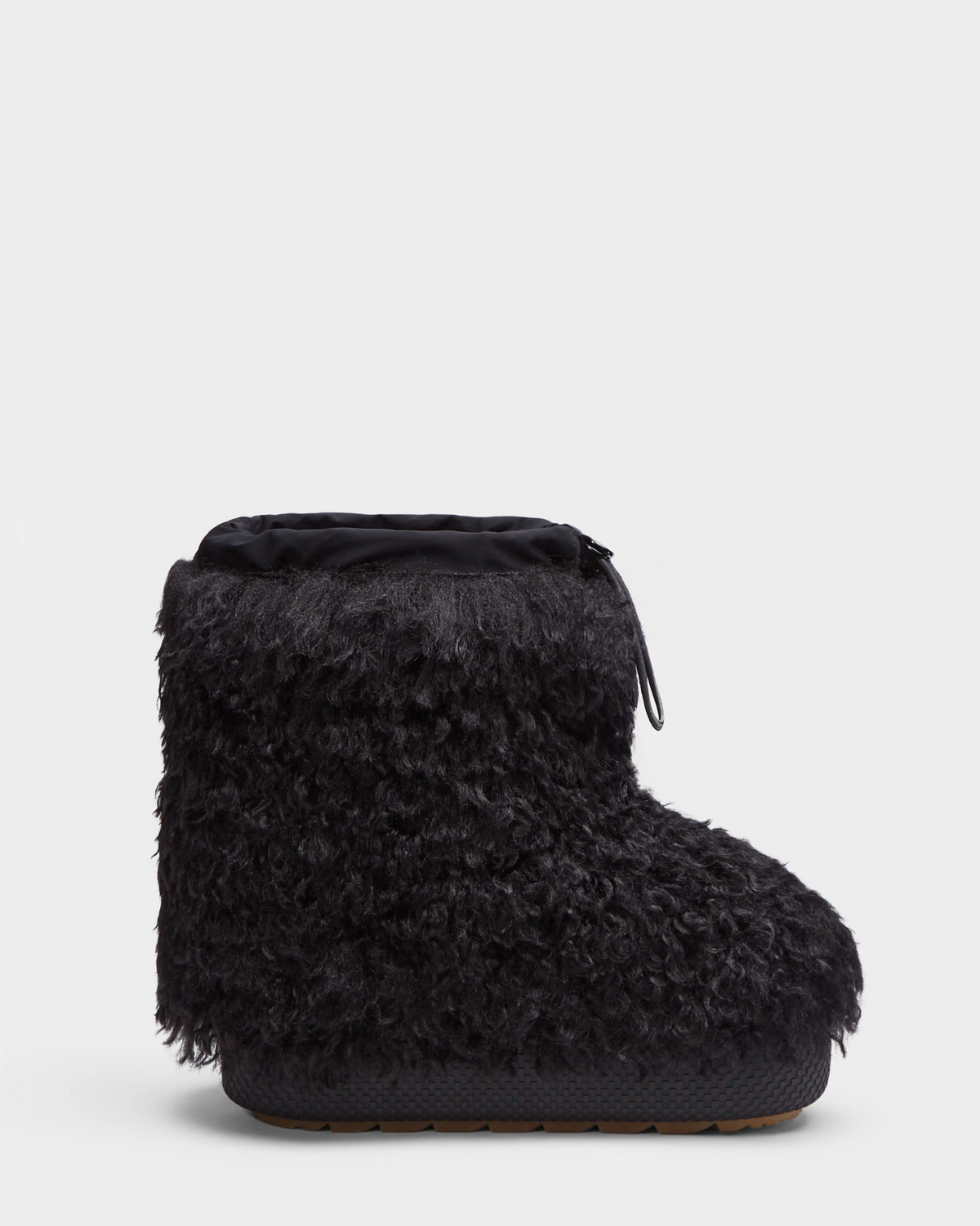 The Rudsak ROSSY - 8224518 Black is a single black slip-on winter boot with a thick, curly faux fur exterior, rounded toe, and flat rubber sole, inspired by Mongolian fur boots and displayed against a plain white background.