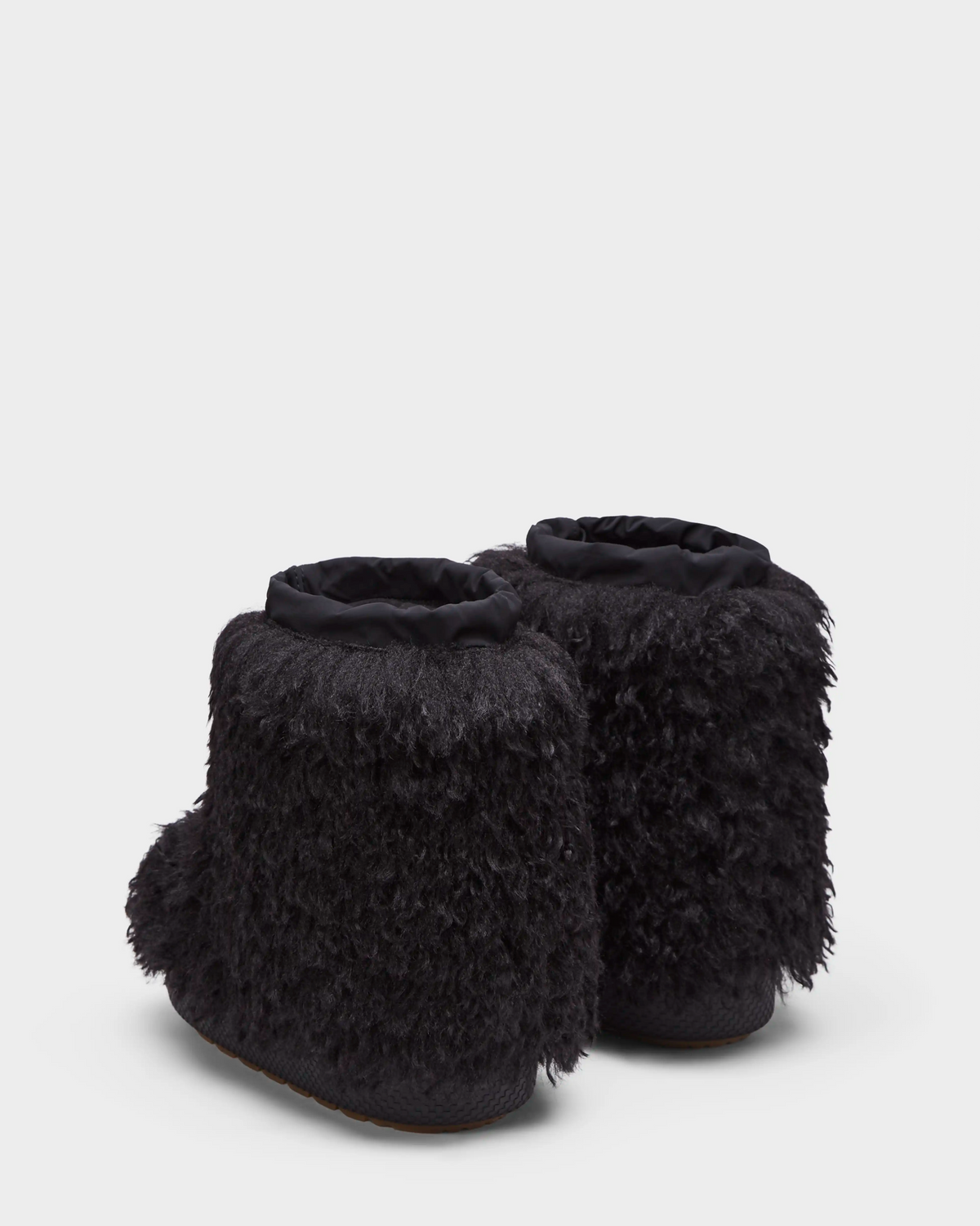 The ROSSY - 8224518 Black slippers by Rudsak feature a shaggy, Mongolian fur-inspired black exterior and are shown from the back against a plain white background.