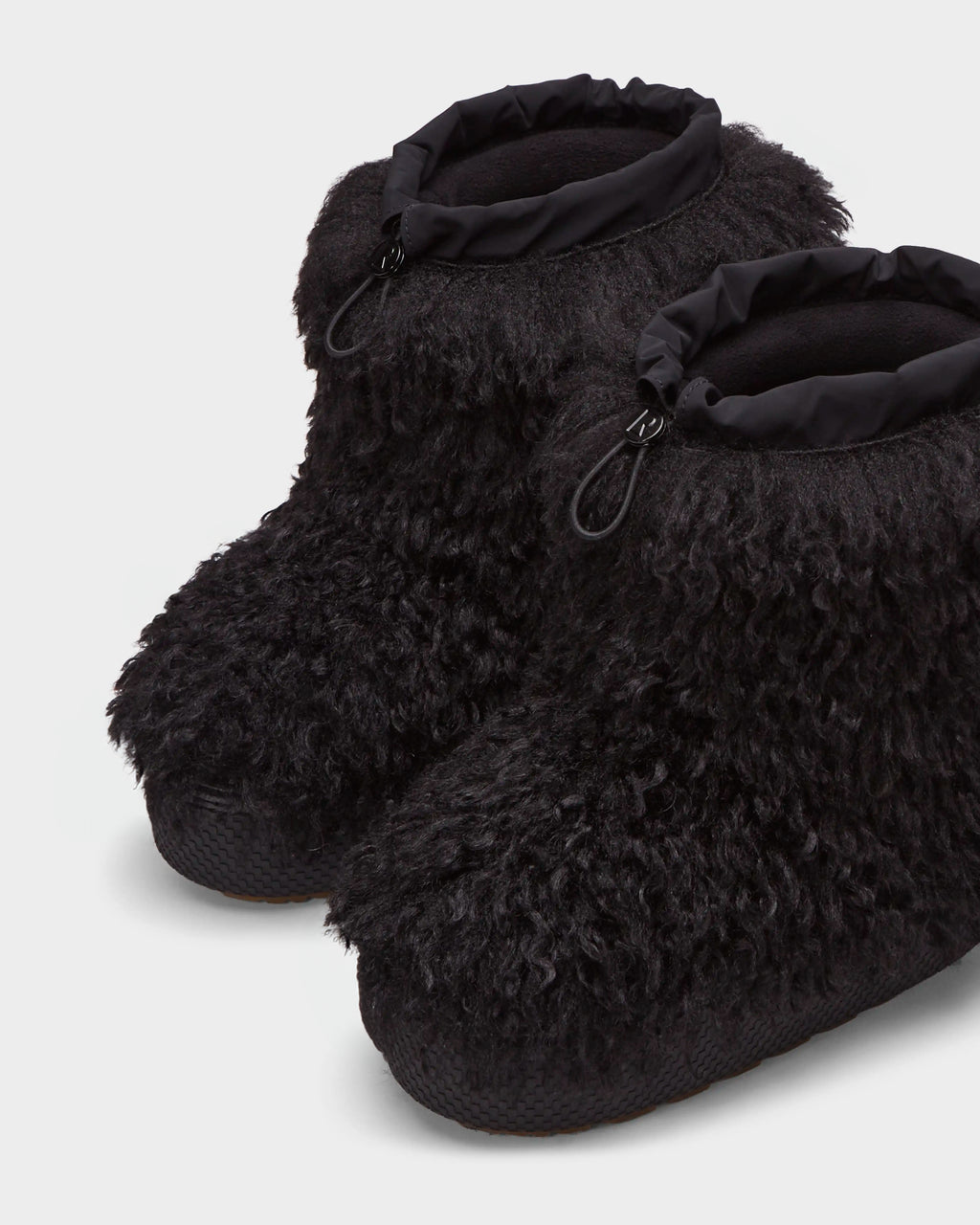 The ROSSY - 8224518 Black by Rudsak are black, fluffy ankle-high slipper boots featuring textured soles and adjustable drawstring tops, styled like womens winter boots and shown on a light background.