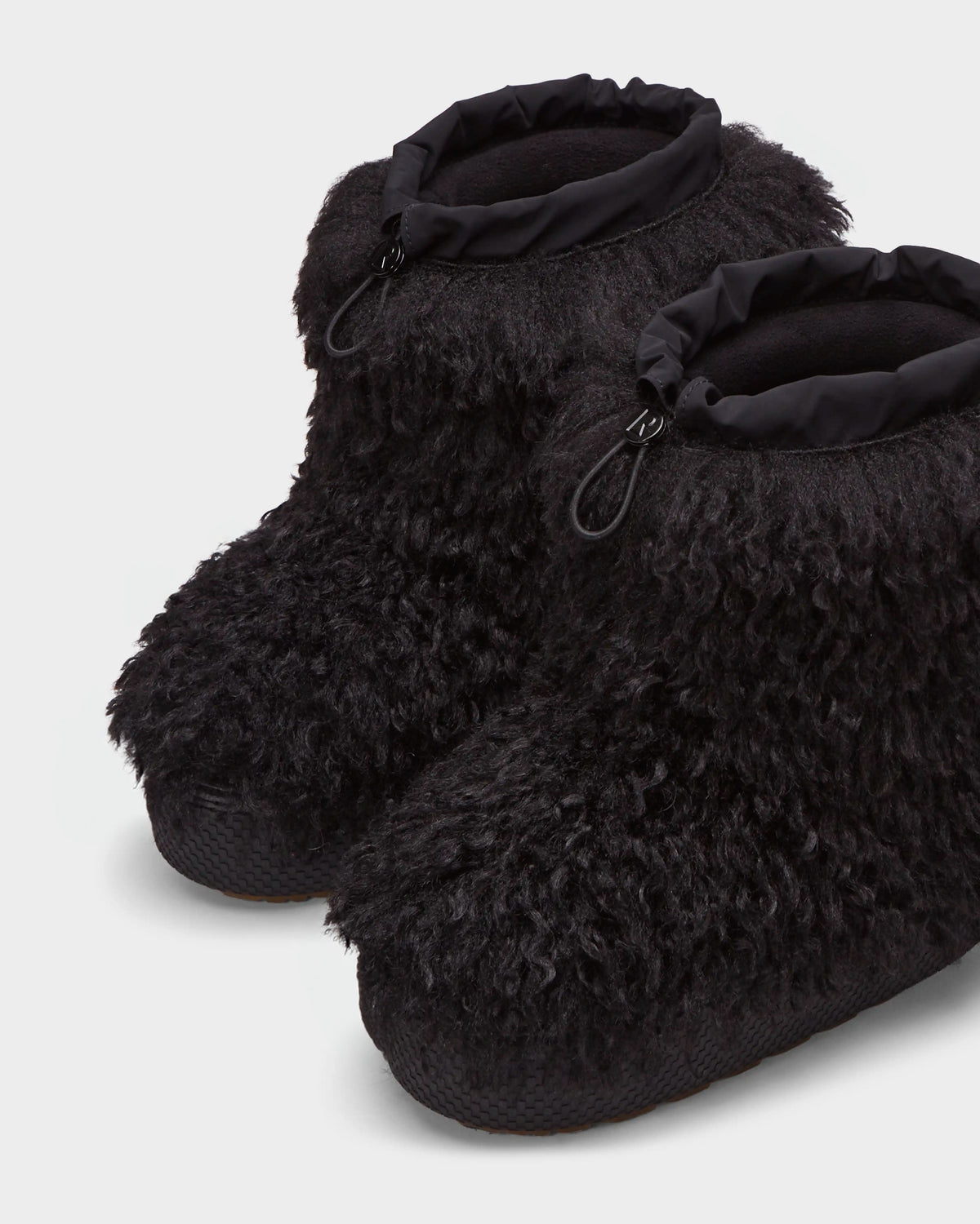 The ROSSY - 8224518 Black by Rudsak are black, fluffy ankle-high slipper boots featuring textured soles and adjustable drawstring tops, styled like womens winter boots and shown on a light background.