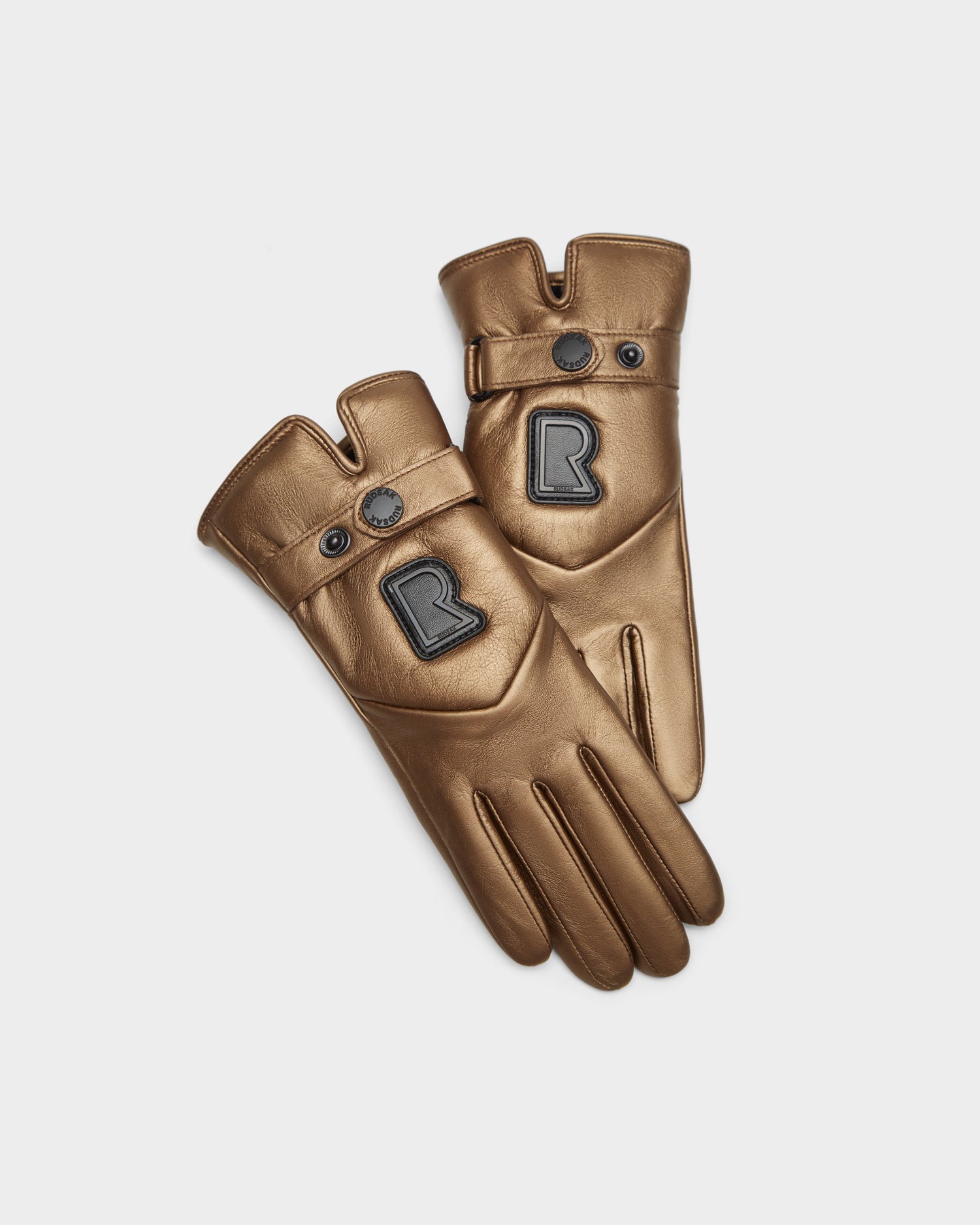 The Rudsak STROMBOLI - 8424510 Antique Bronze women's leather gloves feature black trim, buttoned straps, and a bold black R logo patch—stylish touchscreen winter gloves shown on a white background.