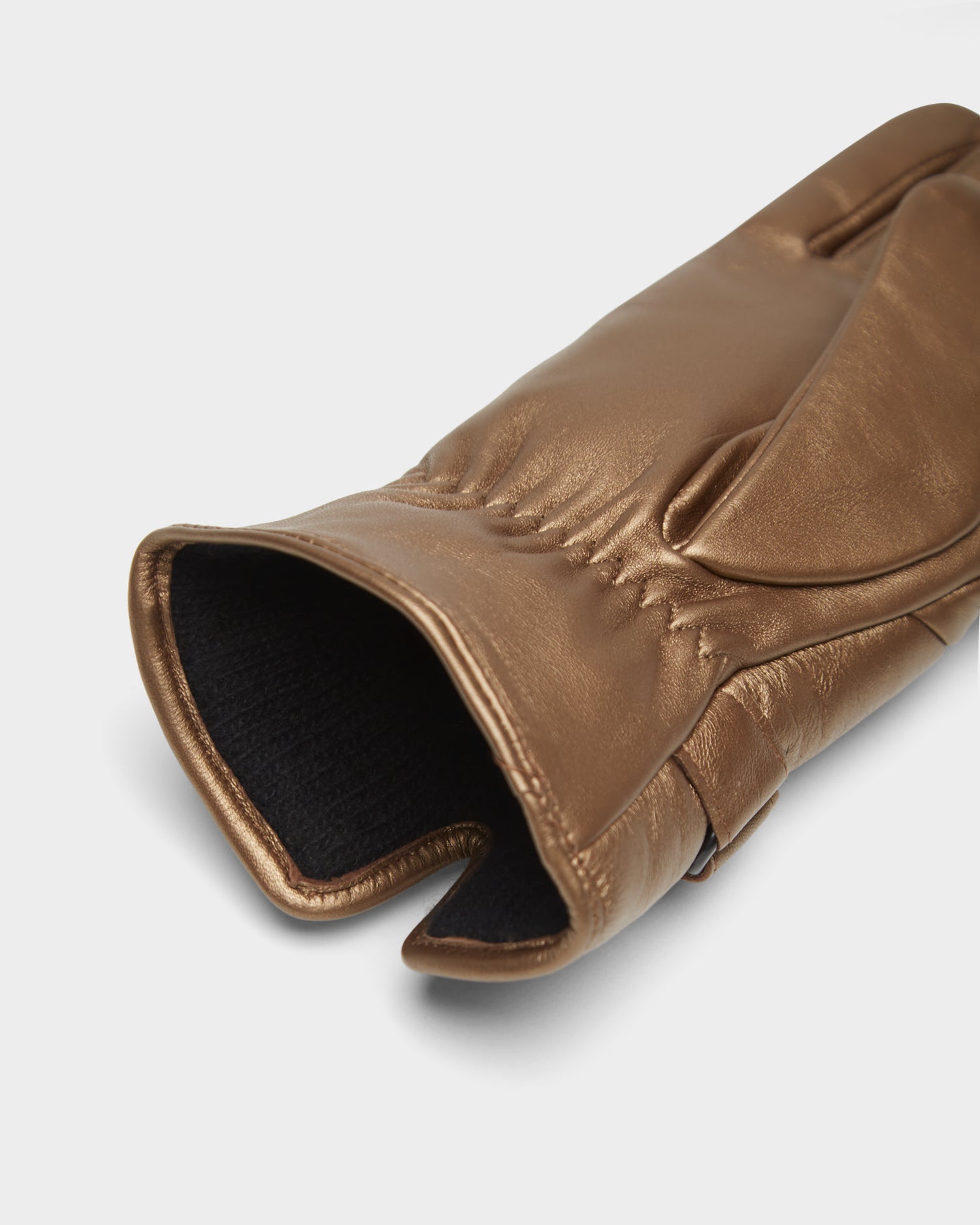 A close-up of the Rudsak STROMBOLI - 8424510 women's leather glove in antique bronze, featuring a partially open cuff that reveals a black inner lining, set against a plain white background.