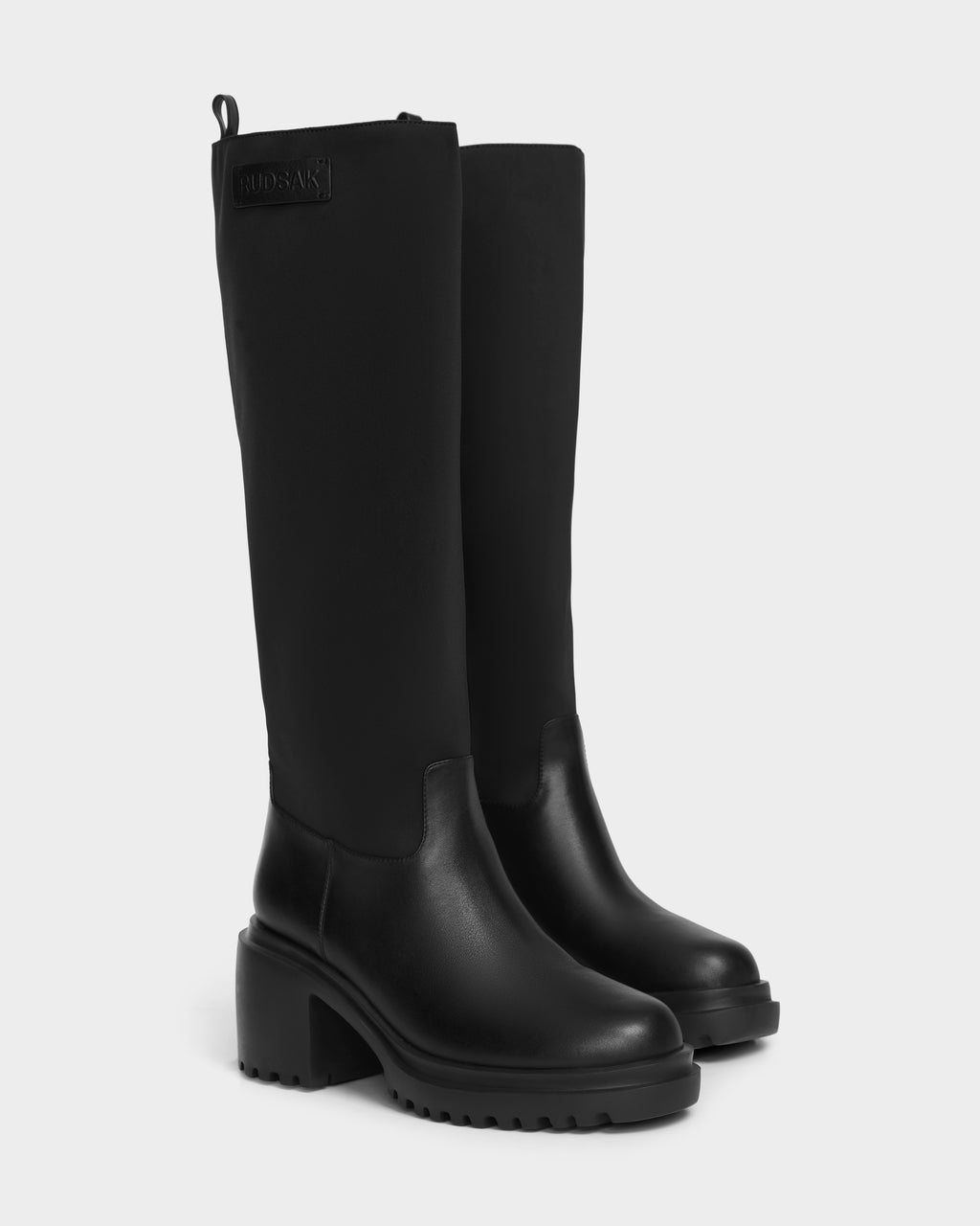 The TIARA - 8224529 Black boots by Rudsak feature chunky heels, rugged soles, a smooth leather lower and fabric upper, all in black, displayed against a plain white background.