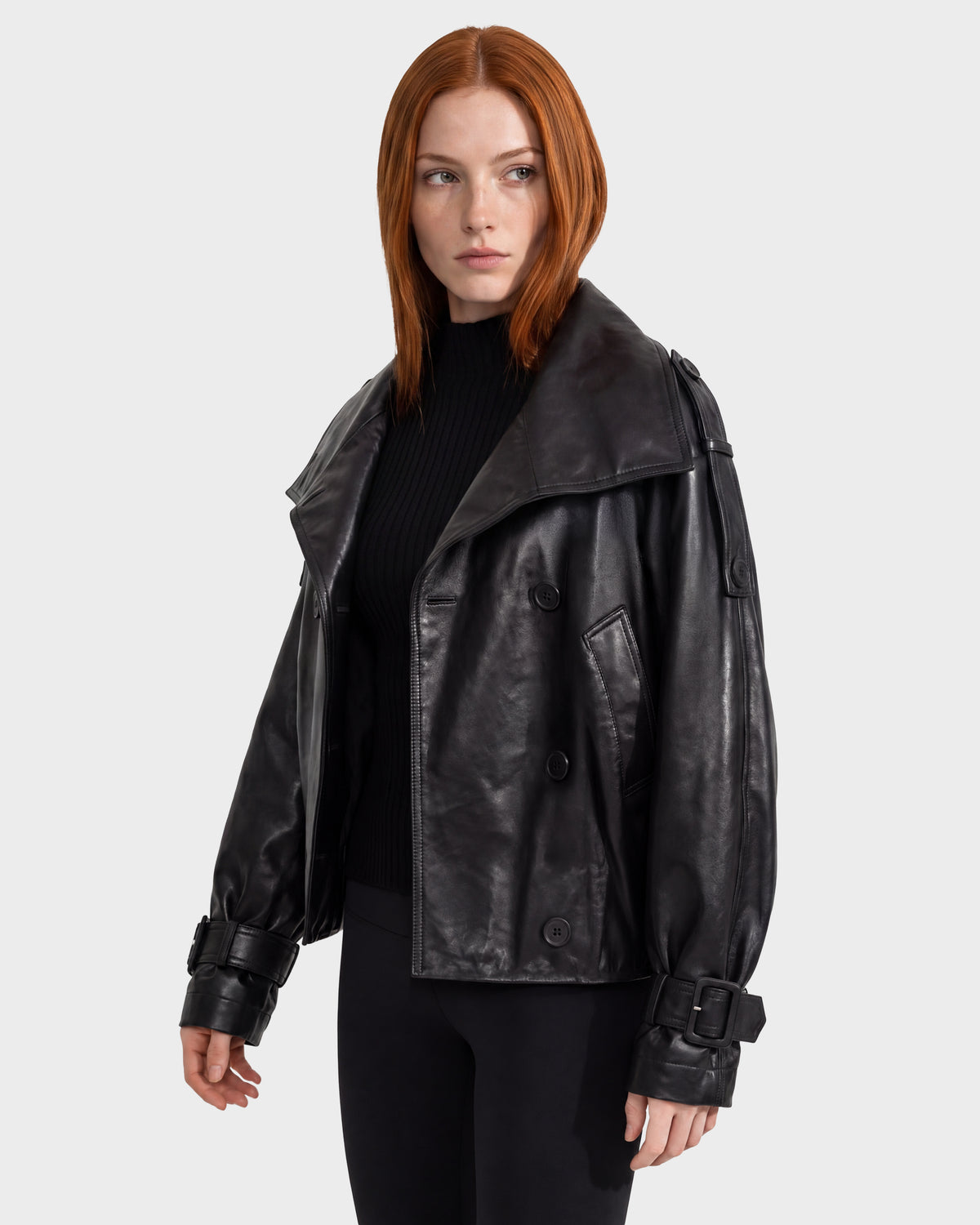 The Rudsak JANELLE - 8126936 Black leather bomber features a modern silhouette with a wide collar, buckled cuffs, and a double-breasted closure over a black ribbed sweater.