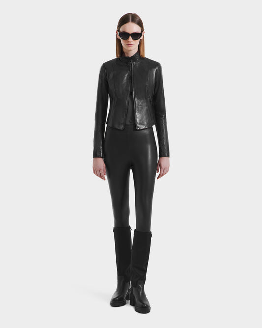 A person in black sunglasses, Rudsak's ABIGAIL N - 8125970 Black women's leather racer jacket, black leggings, and knee-high boots stands facing forward against a plain white background.