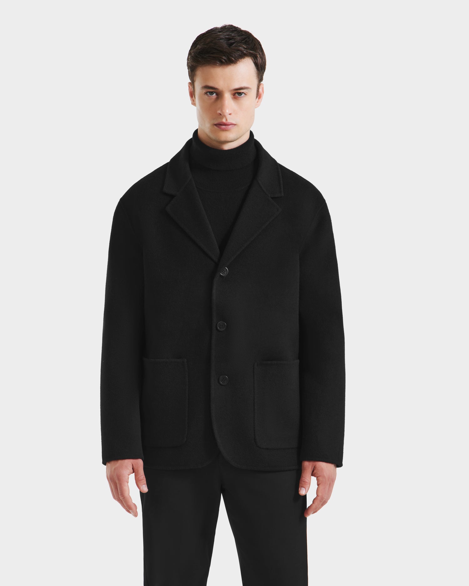 A man in the Rudsak AIDEN - 6125558 Black men’s wool-blend coat with a removable faux shearling collar, showcasing refined outerwear style.