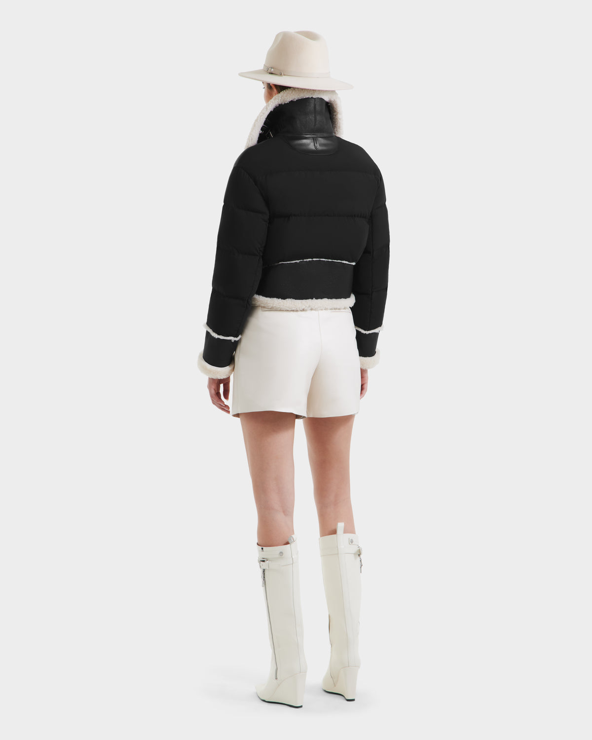 Someone wears the ANA - 8125508 Black jacket by Rudsak, white shorts, knee-high white boots, and a beige hat, standing with their back to the camera against a plain background.