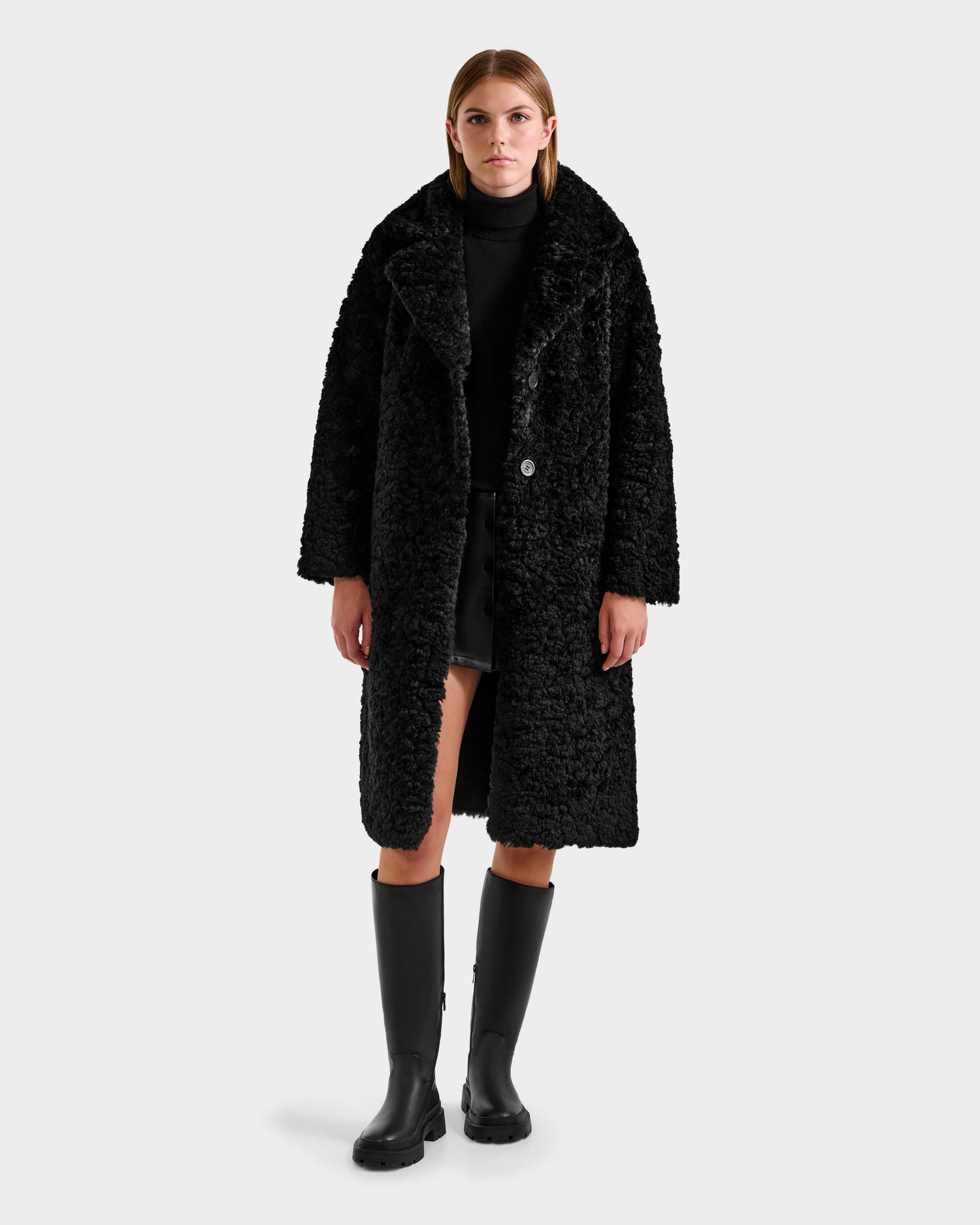 A woman exudes effortless elegance in the Rudsak ANNABELLE FSU - L125512 Black, a stylish women’s reversible trench coat that showcases timeless sophistication.