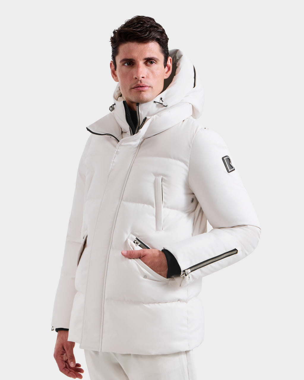 A man wears the Rudsak APOLLO H - 6125690 Vanilla men’s quilted down parka with zippered pockets and vegan leather trim, standing against a plain white background.