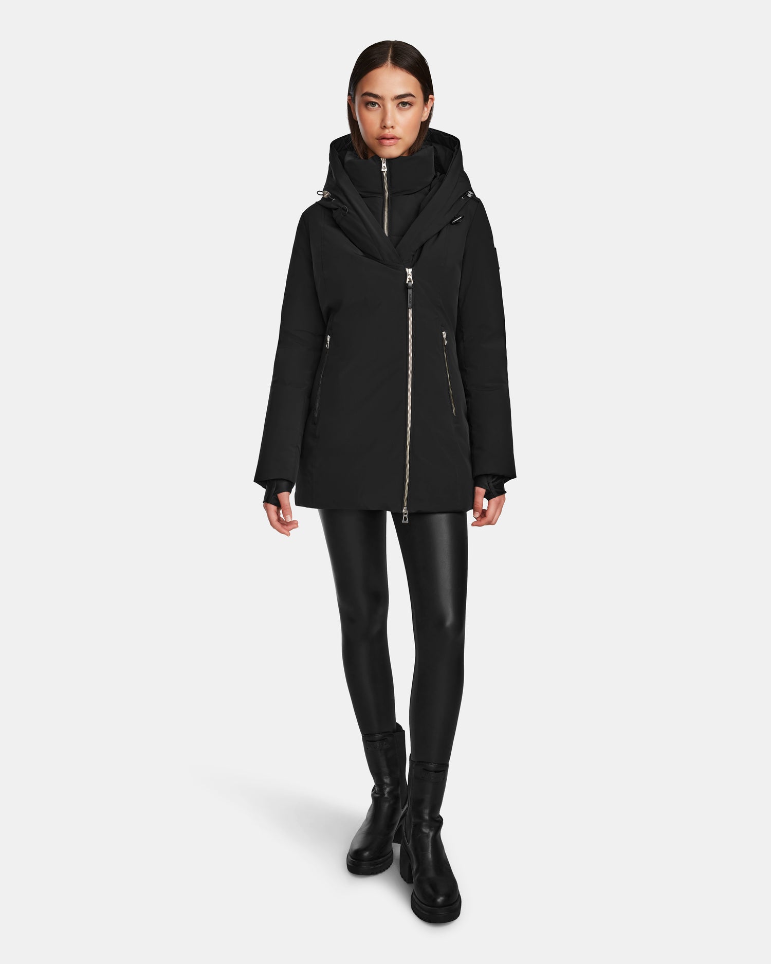 A woman faces forward, wearing the Rudsak AURORE - L123561 Black/Black women's short fitted down parka, styled with faux leather leggings and ankle boots against a plain white background.