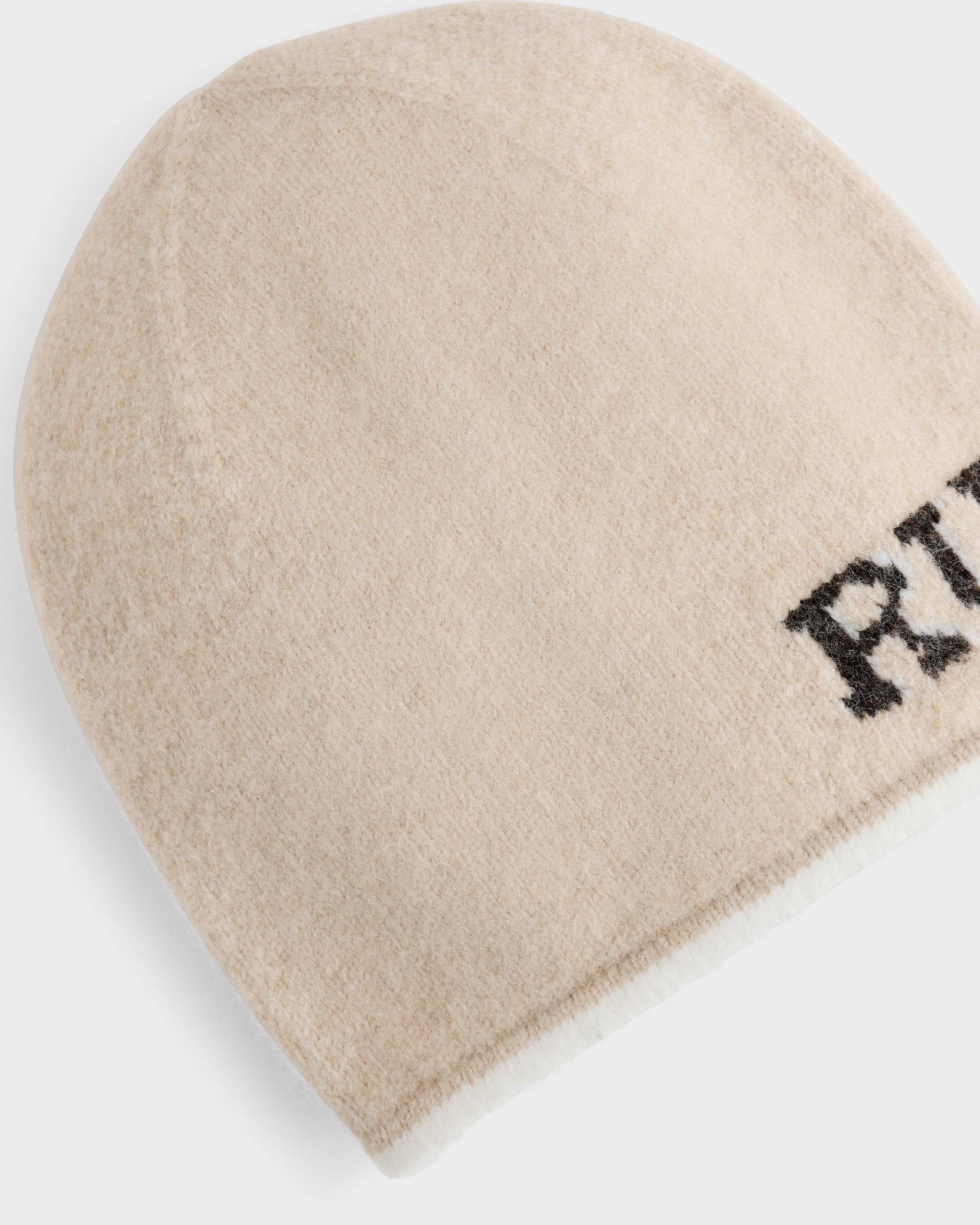 The AXEL - 6425040 Vanilla beanie by Rudsak is a beige knit winter accessory with black text partially visible on one side, shown against a white background.