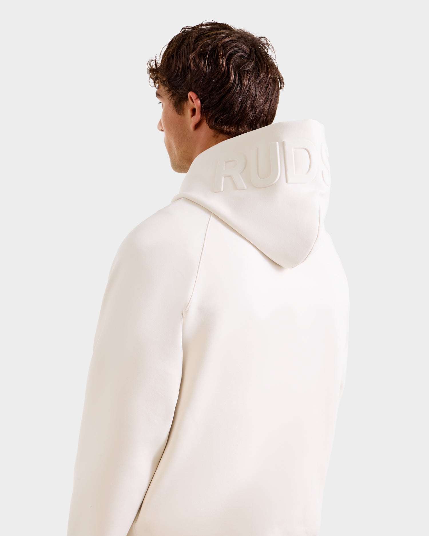A person with short brown hair is seen from behind wearing the Rudsak BARRY - 9524011 hoodie in Vanilla M, an off-white oversized style with "RUDS" embossed on the hood, photographed against a plain light background.