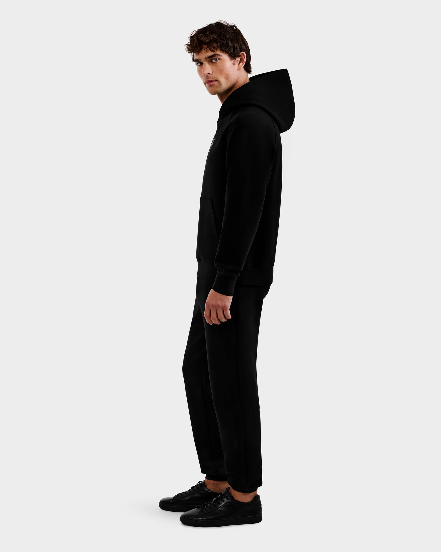 A young man wearing the Rudsak BRIAR - 9525001 Black M hoodie stands sideways, facing slightly toward the camera, against a plain white background.