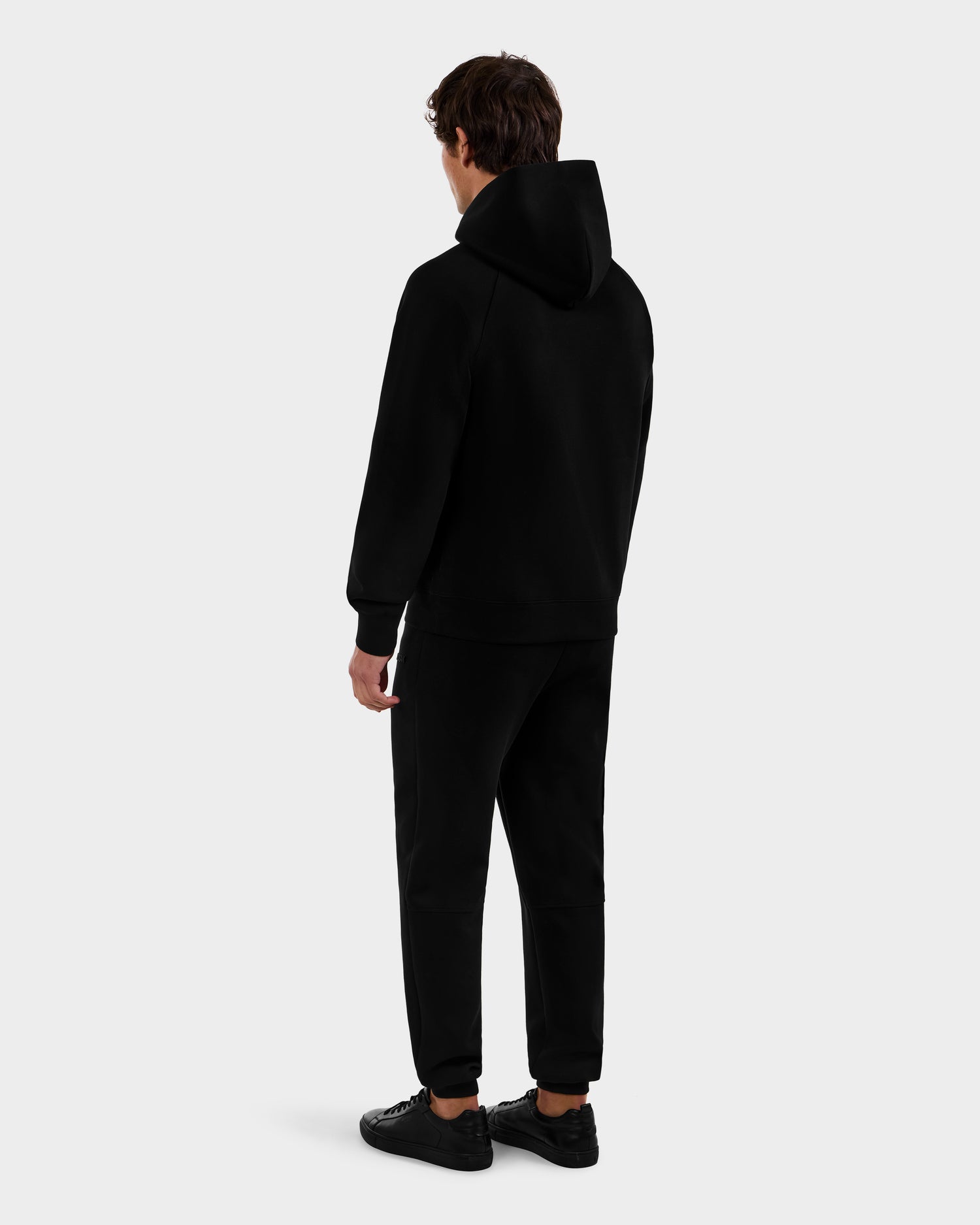 A person in the Rudsak BRIAR - 9525001 Black M hoodie stands facing away, looking to the side, against a plain light gray background.
