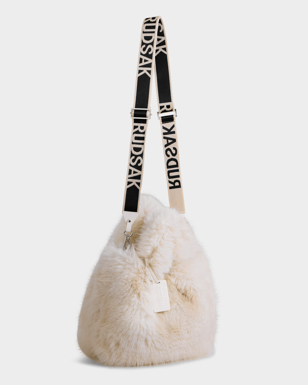 The CABAS - 8325545 Vanilla by Rudsak is a cream-colored faux fur mini tote with a wide black strap featuring white RUDSAK text, minimalist design, and small tag—a standout winter accessory.